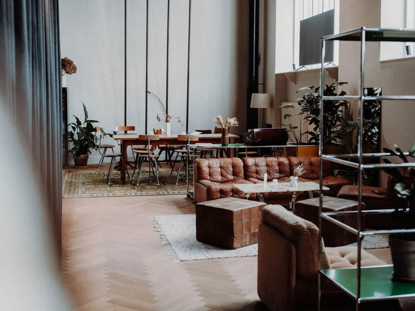 Gemütlicher Raum mit Sofas, Pflanzen und einem großen Tisch, ideal für Treffen und Networking-Veranstaltungen.