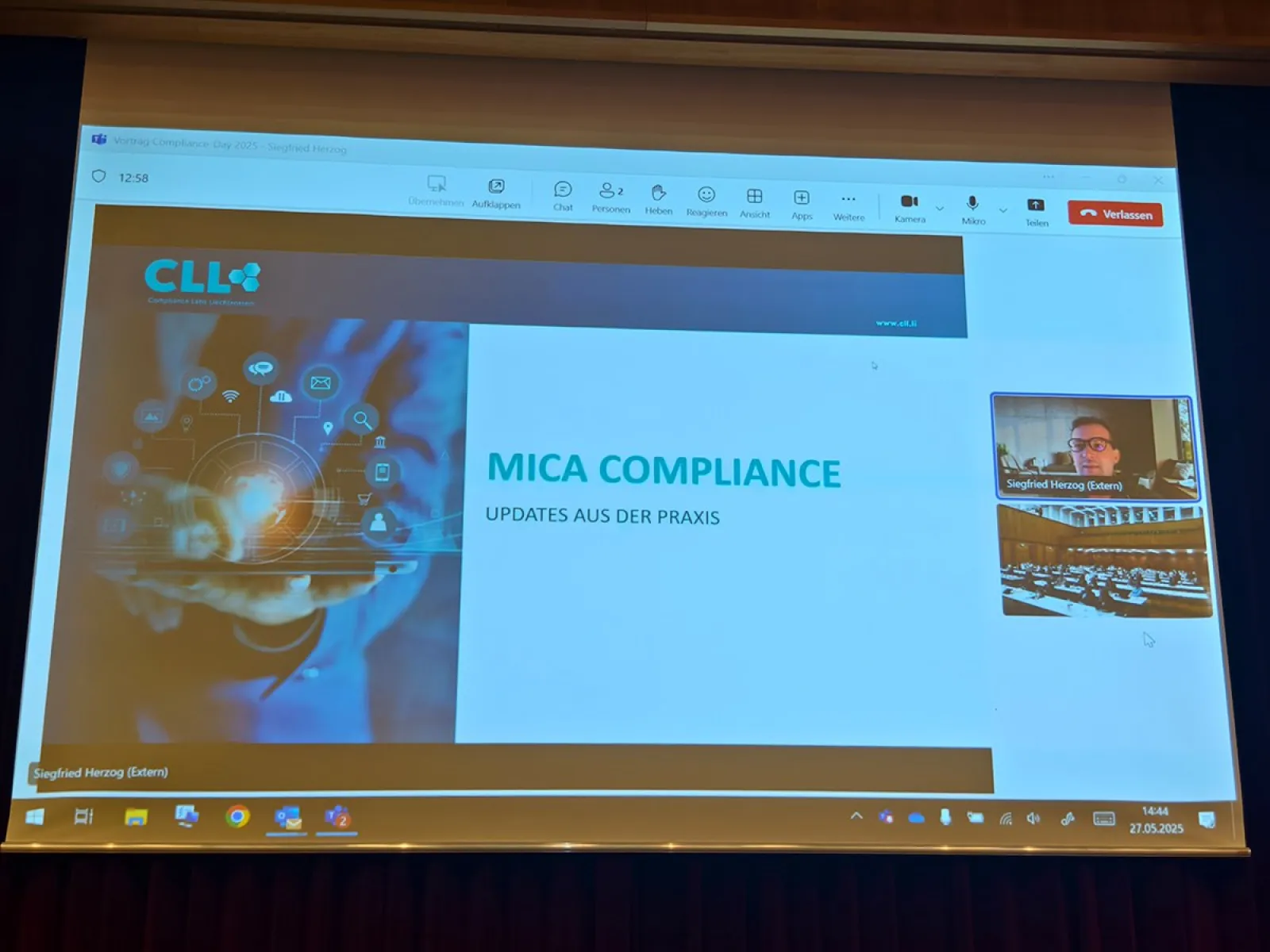 Präsentation auf einer Leinwand mit dem Titel "MICA Compliance: Updates aus der Praxis" beim Compliance-Day 2025 an der Universität Liechtenstein. Links ist ein Bild mit digitalen Symbolen, rechts ein kleines Videofenster mit einem Sprecher.