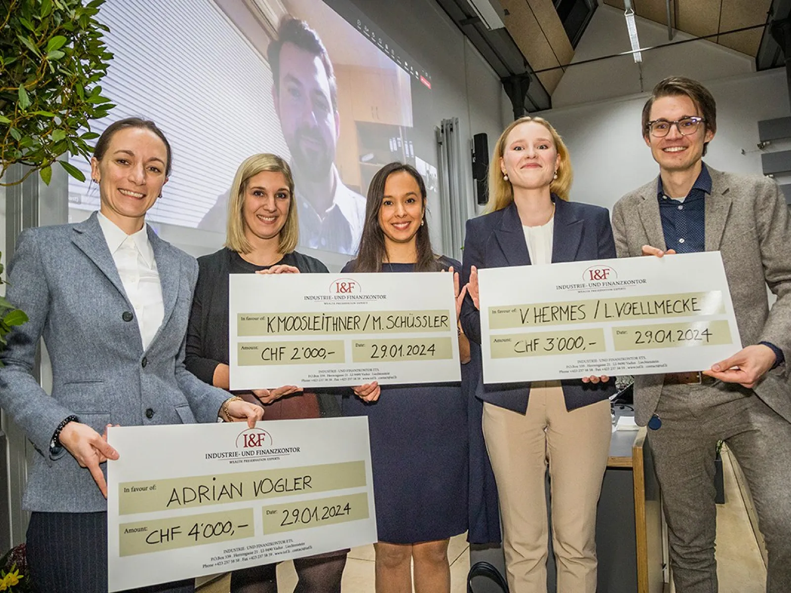 Fünf Studierende der Universität Liechtenstein halten große Schecks als Gewinner des I&F Family Wealth Preservation Awards. Im Hintergrund ist eine Person auf einem Bildschirm zu sehen.