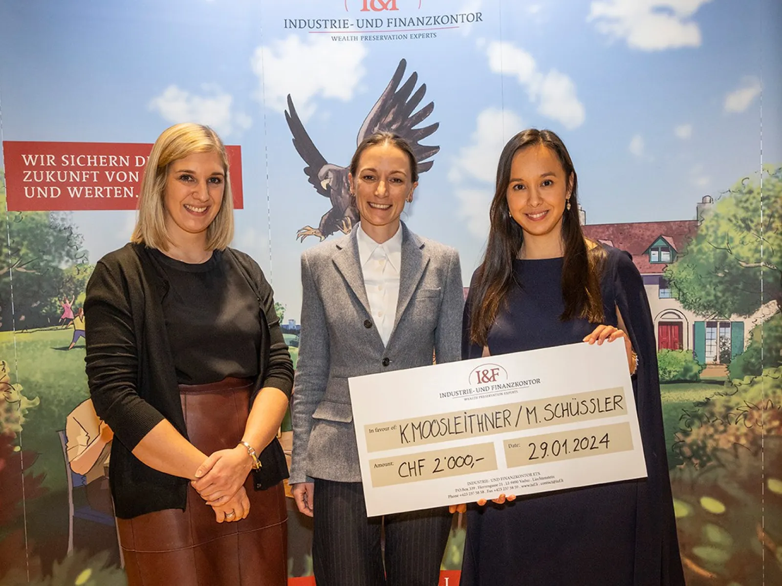Drei Personen stehen lächelnd vor einem Hintergrund mit dem Logo der Industrie- und Finanzkontor. Eine Person hält einen großen Scheck mit der Aufschrift "CHF 2,000" und einem Datum. Im Hintergrund ist ein stilisiertes Bild mit einem Adler und einem Haus zu sehen.