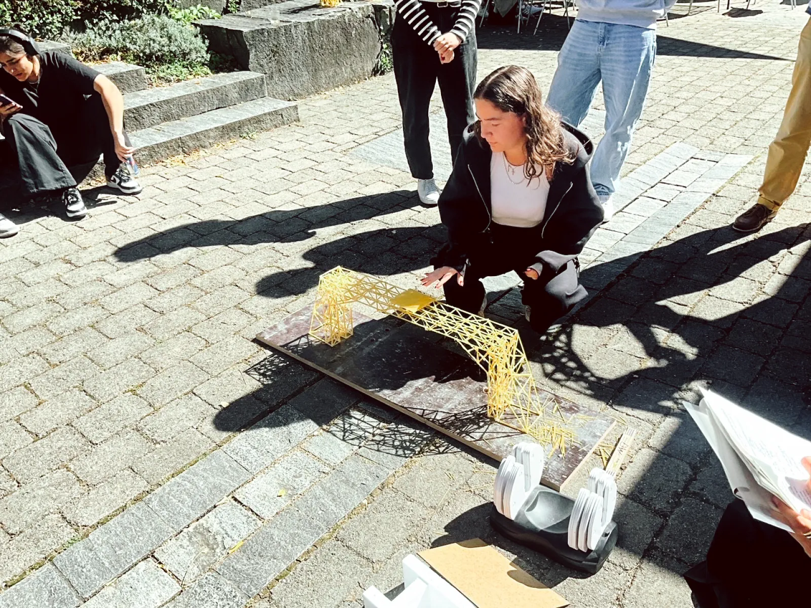 Studierende testet Tragfähigkeit von Spaghettibrücke