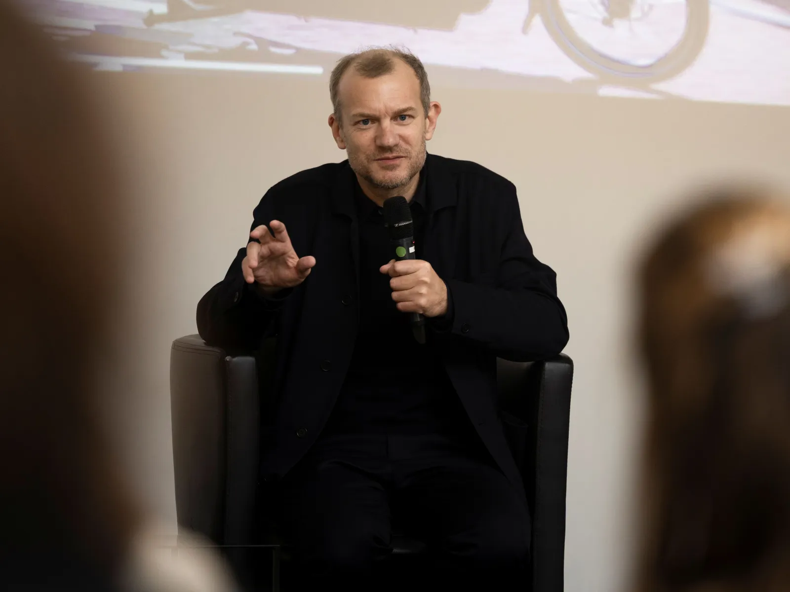 Vortragender mit dunkler Kleidung und einem Mikrofon in der Hand
