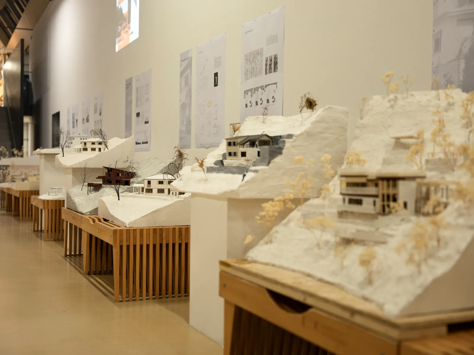 Mehrere Architekturmodelle in beige/weiss auf Holzbänken