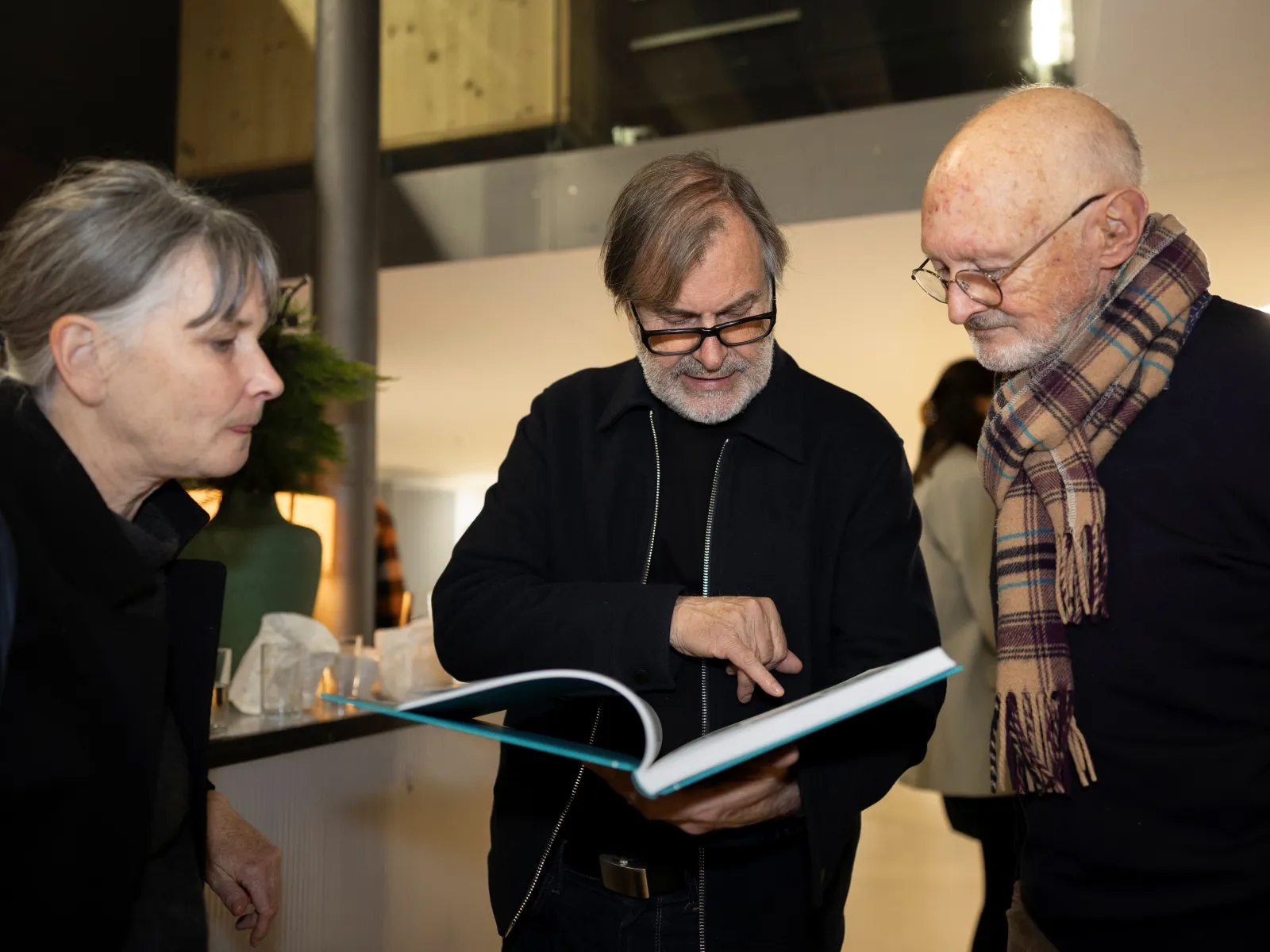 Drei Personen schauen auf ein Buch 