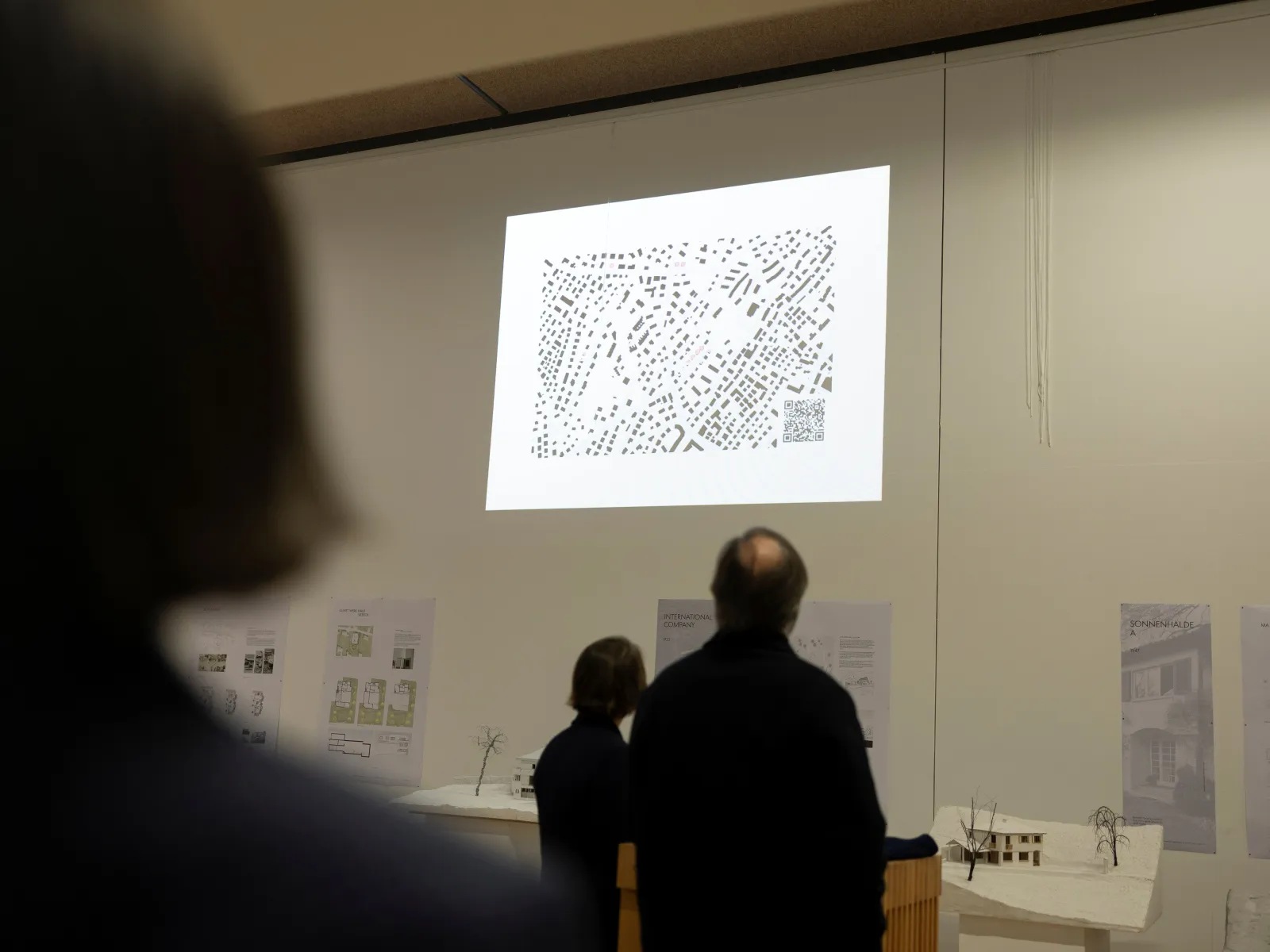 Mehrere Menschen schauen auf eine Leinwand mit einem Plan