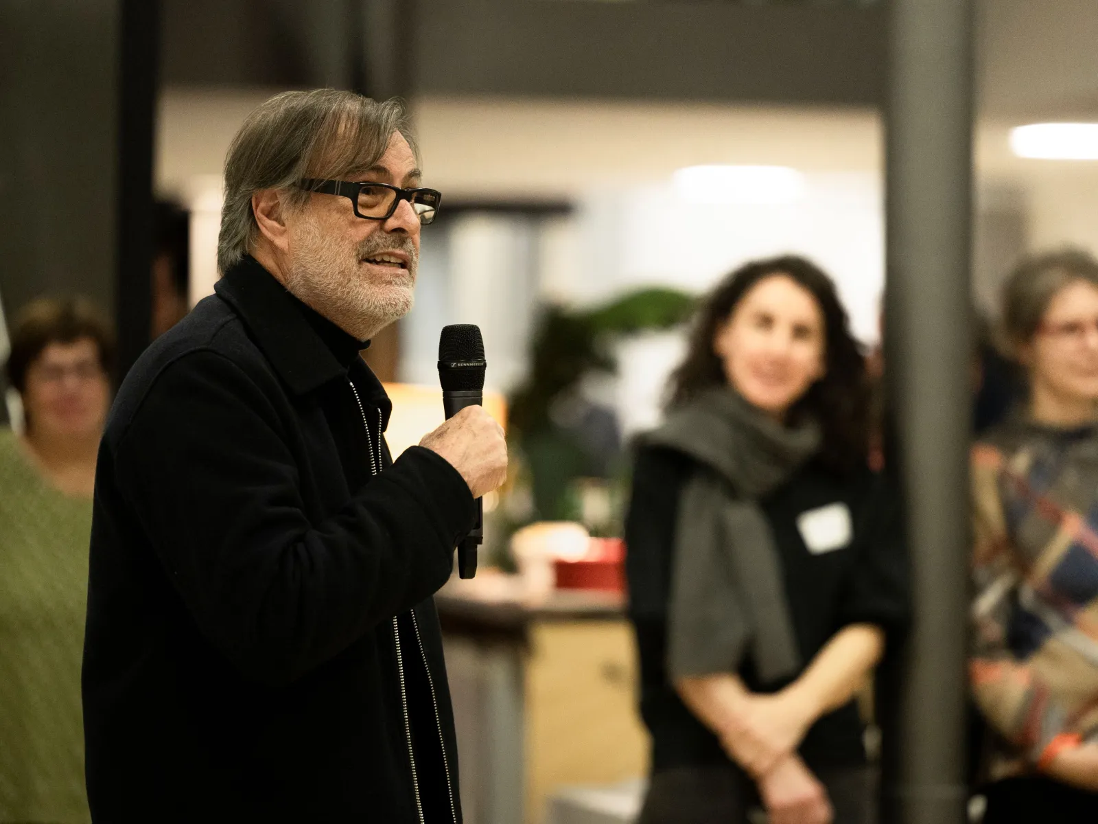 Ein Mann spricht vor einer Gruppe von Menschen mit einem Mikrofon in der Hand 