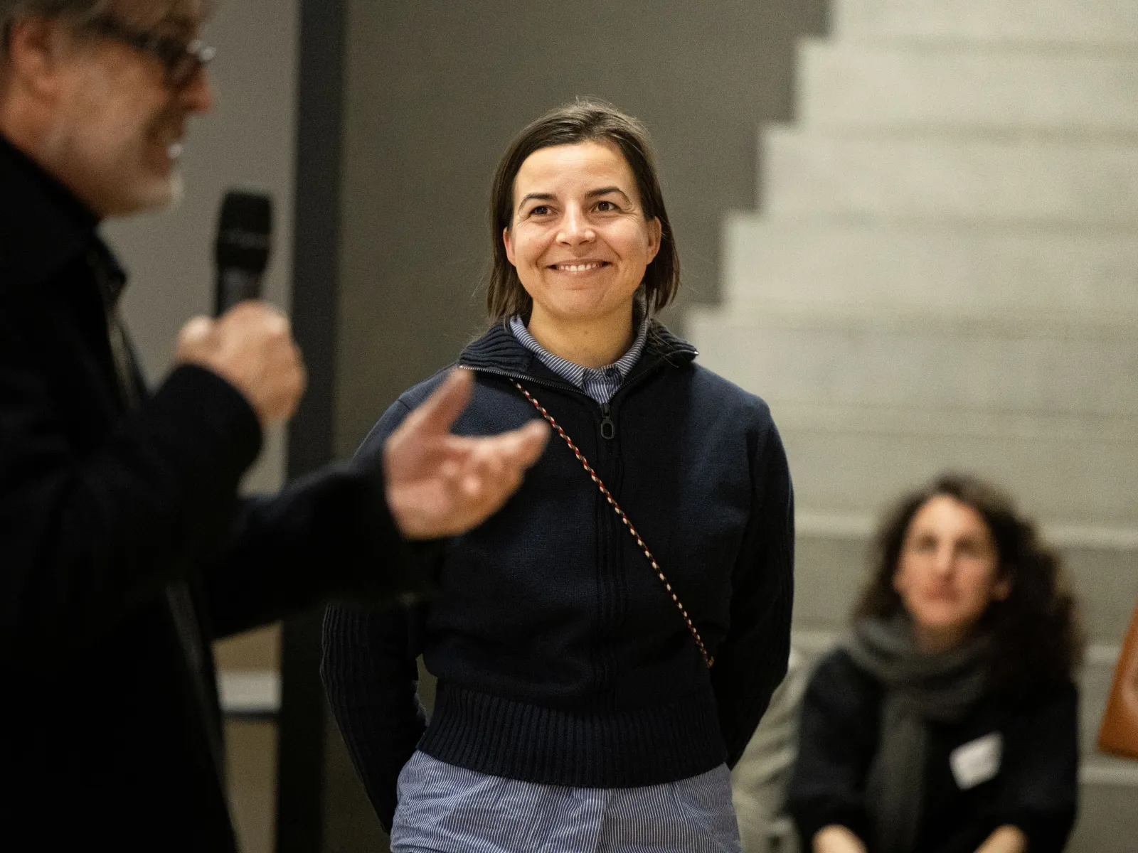 Eine Frau mit dunklen Haaren und dunkelblauem Pullover 