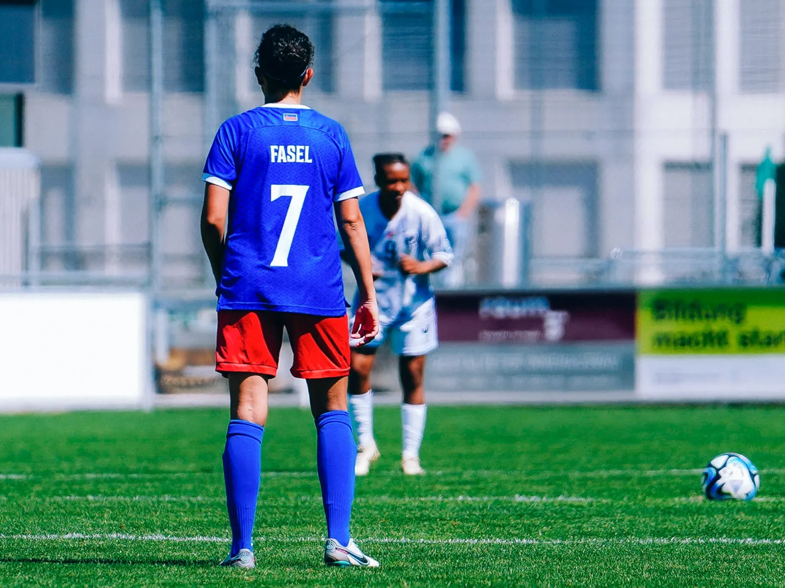 Fussballspielerin beim Anstoss auf dem Spielfeld während eines Spiels mit Gegnerin im Hintergrund