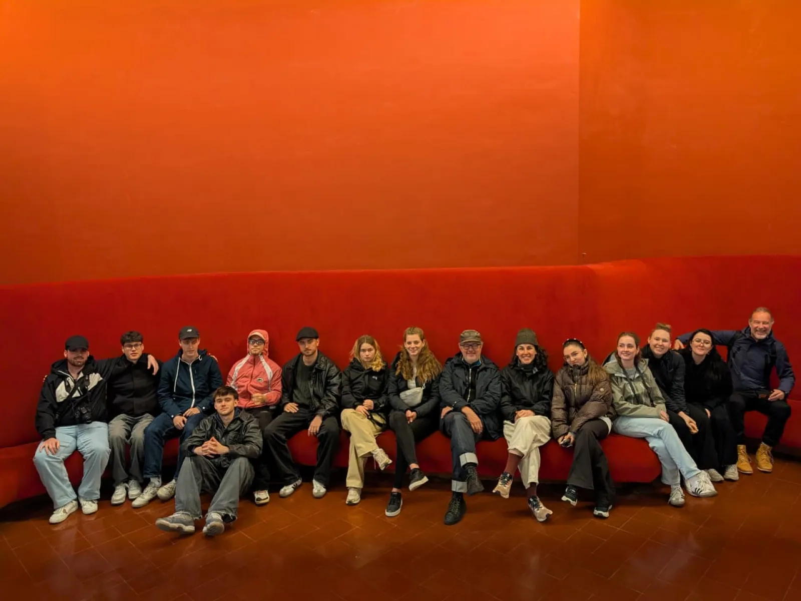 Gruppenfoto von Studierenden mit rotem Hintergrund