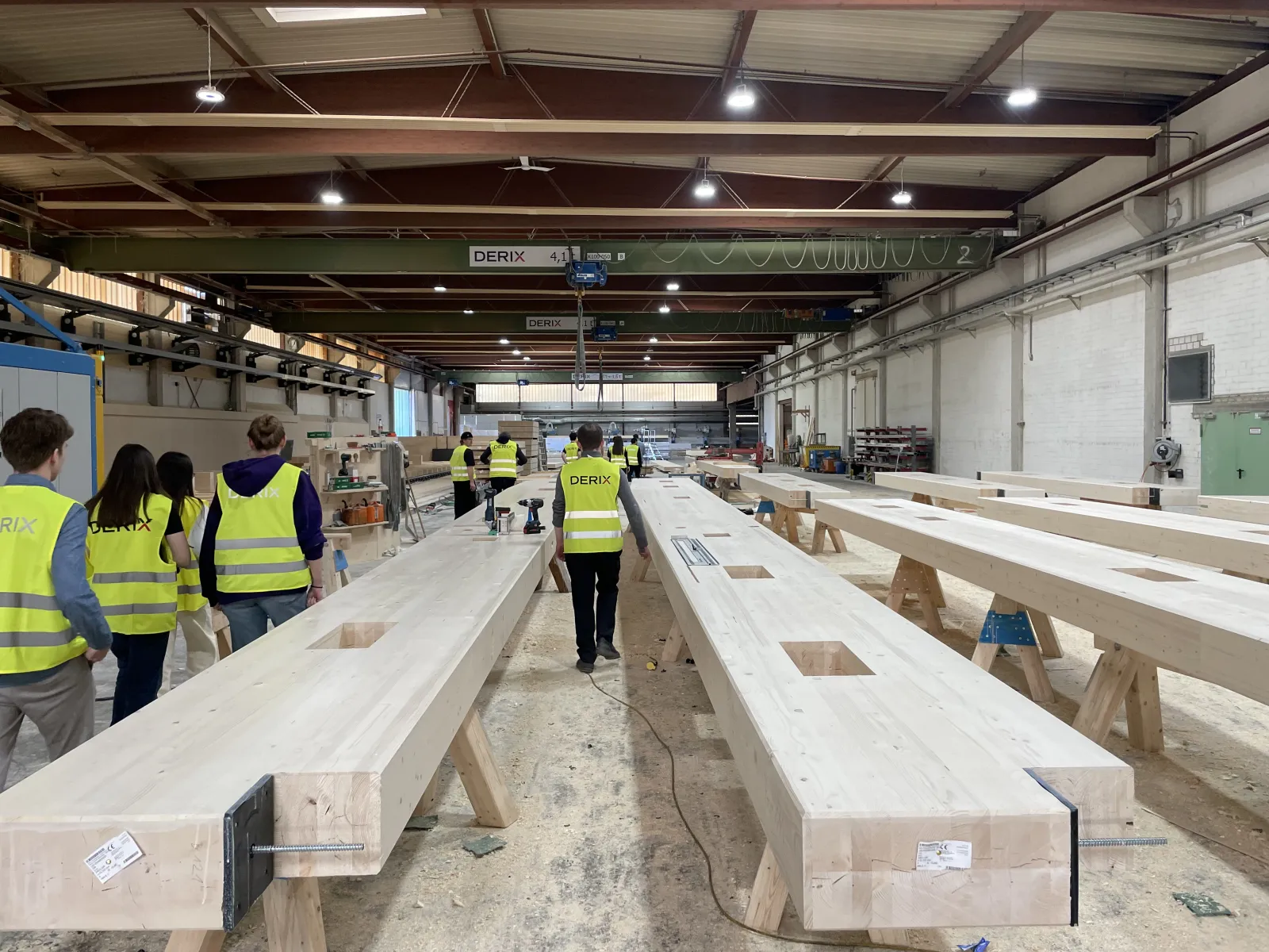 Gruppe von Studierenden läuft durch eine Produktion mit Holzelementen