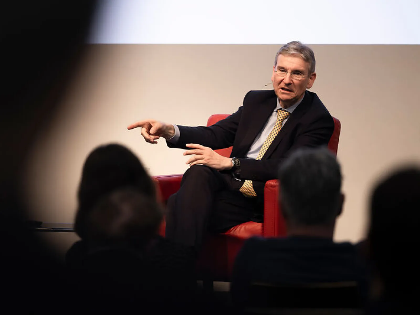 Gesprächspartner gestikuliert im roten Sessel beim Campus-Gespräch der Universität Liechtenstein