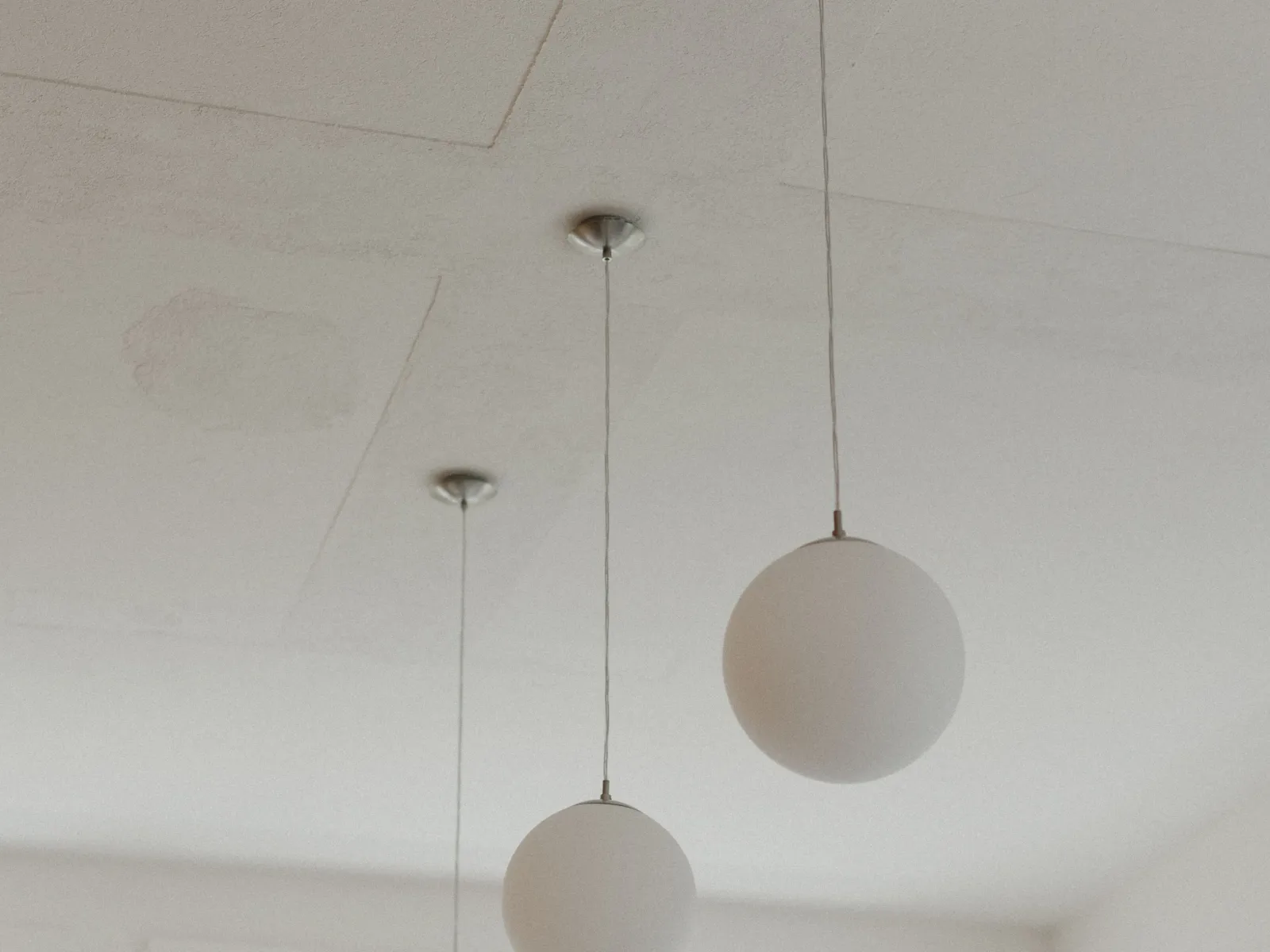 Mehrere weisse Hängeleuchten in einem weissen Raum