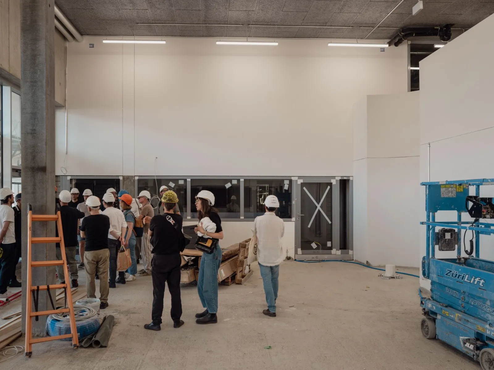 Eine Gruppe von Menschen mit Bauhelmen, die auf einer Baustelle geführt werden. 