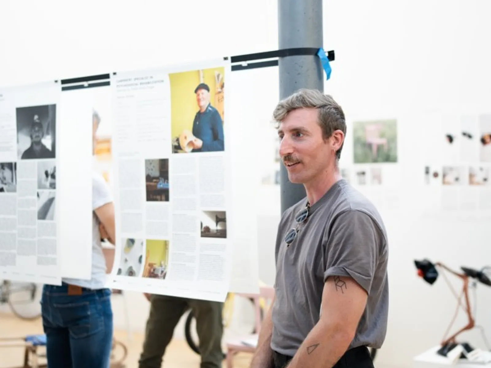 Ein Mann mit kurzer schwarzer Hose und grauem Shirt eröffnet eine Ausstellung