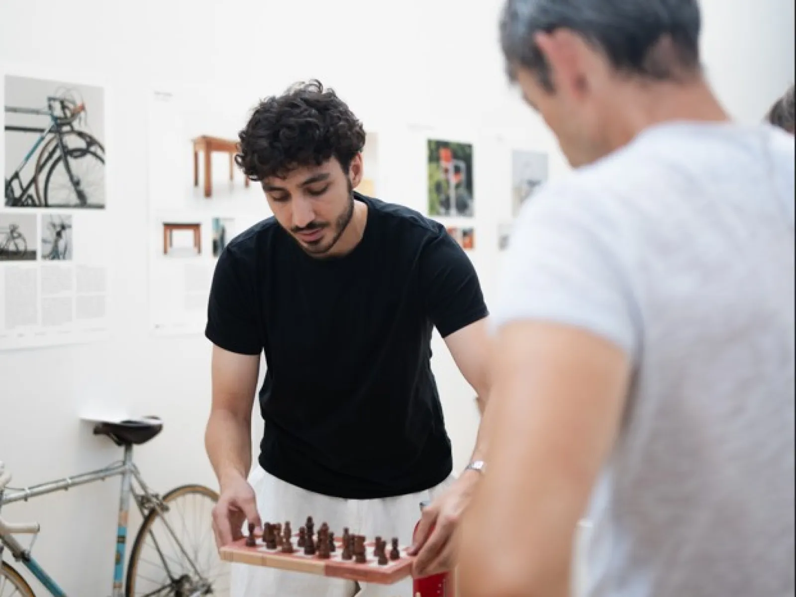 Ein Mann mit schwarzem Shirt stellt ein Schachbrett auf einen Ausstellungsbock 