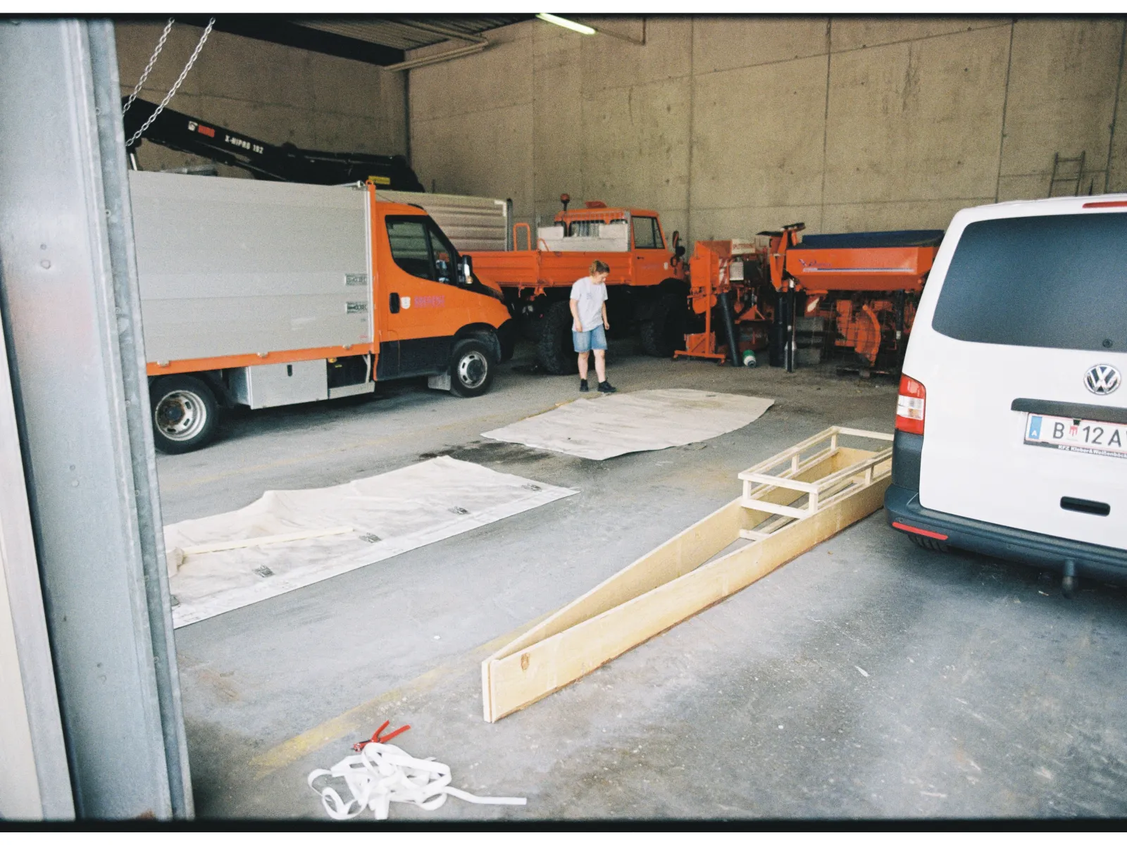 Eine Werkstatt mit Fahrzeugen und einem Holzgerüst für ein Boot. 