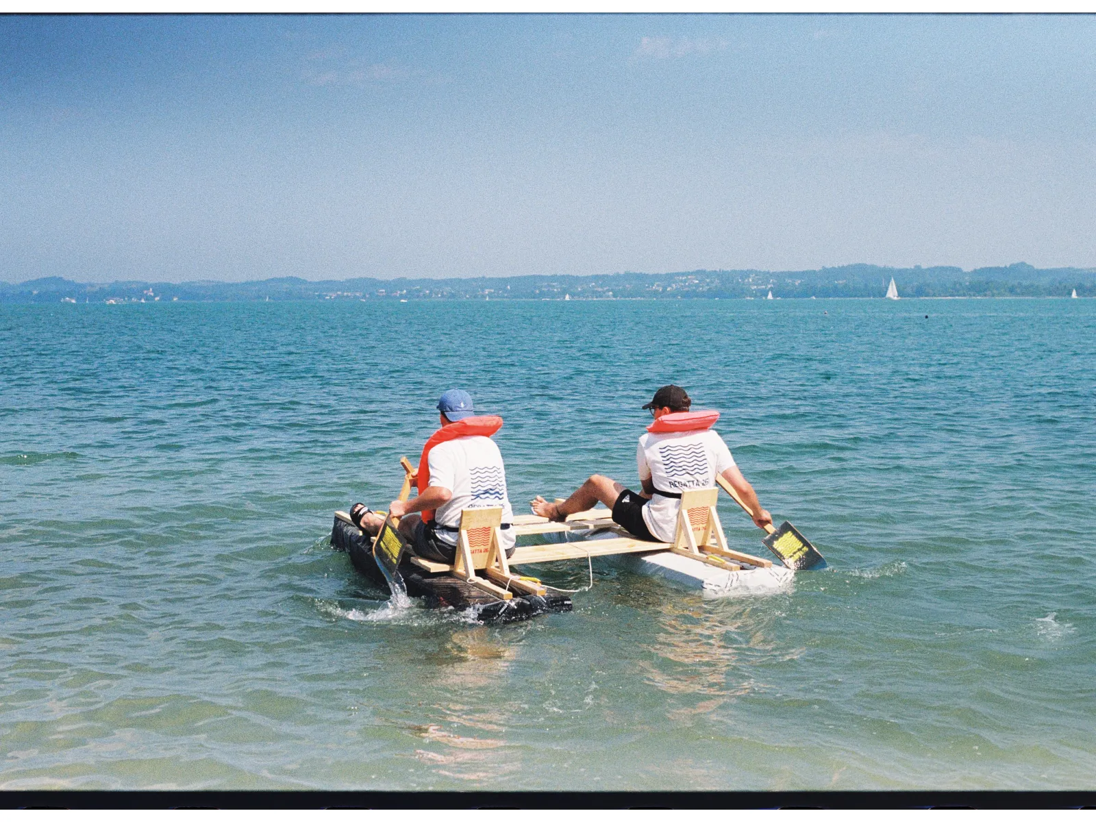 Zwei Menschen mit Schwimmweste in einem selbstgebauten Boot. 