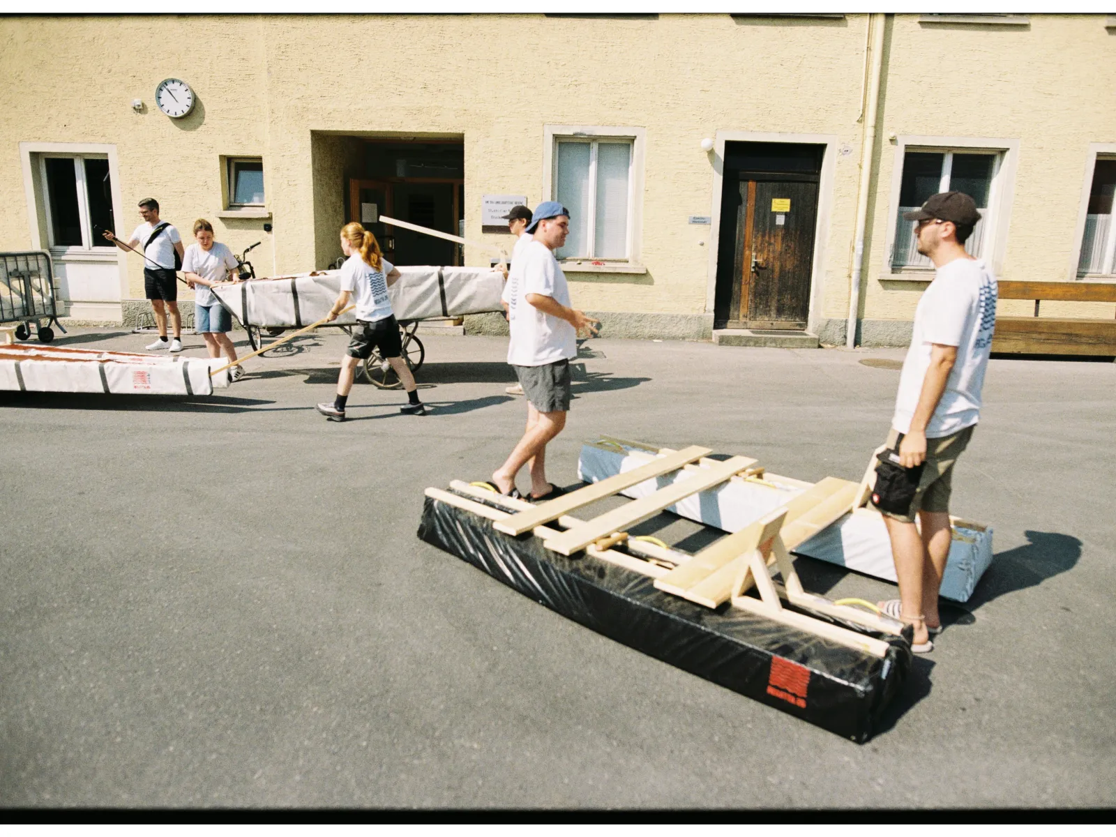 Mehrere Menschen transportieren selbstgebaute Boote aus Holz und Plastikfolie. 