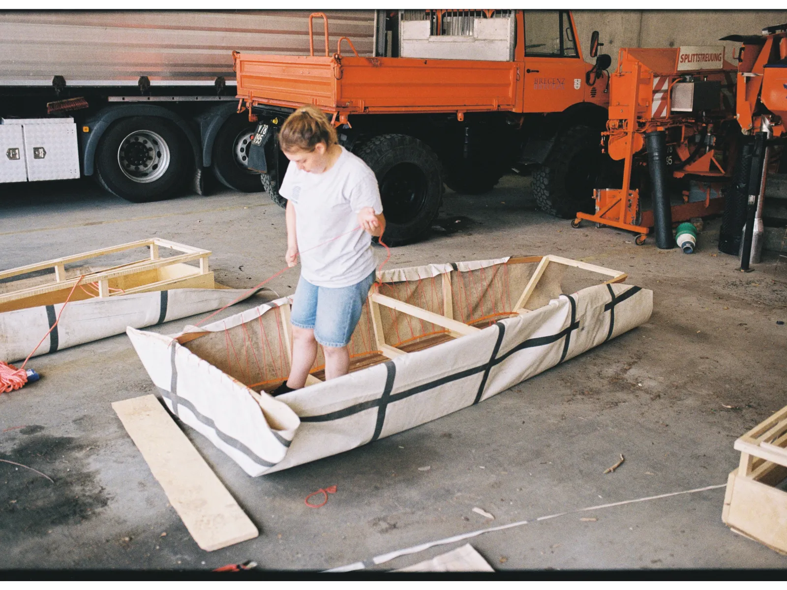 Eine junge Frau steht in einer Werkstatt in einem selbstgebauten Boot. 