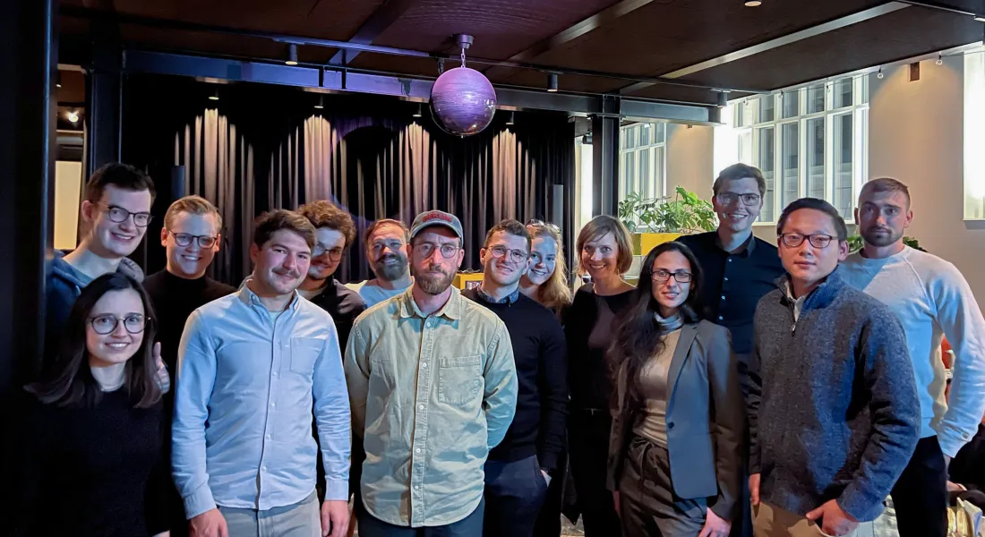 Alumni Gruppe posiert gemeinsam für ein Gruppenfoto bei einer Abendveranstaltung mit stimmungsvoller Beleuchtung.