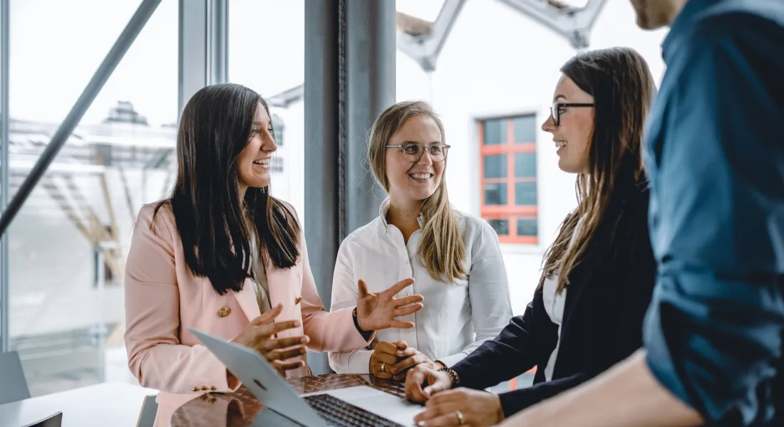 Eine Gruppe Studierende stehen im Gebäude der Universität Liechtenstein um einen Tisch