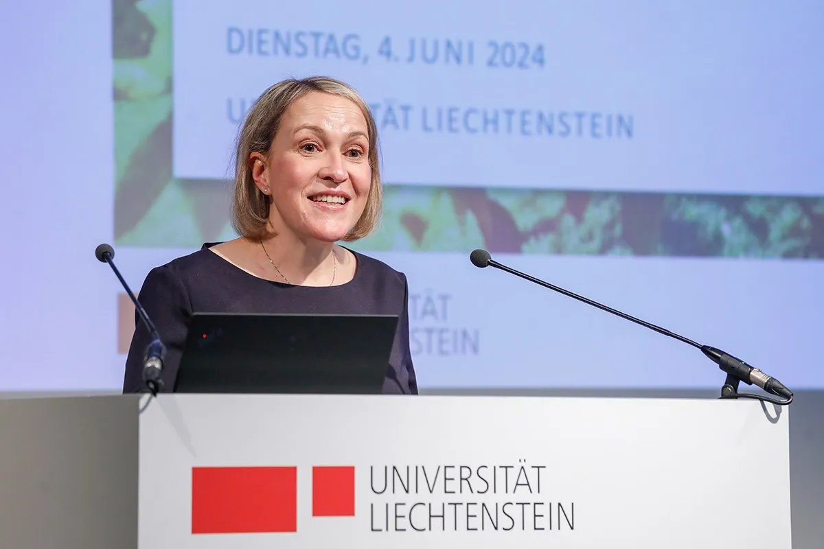 Eine Frau hält eine Rede am Rednerpult der Universität Liechtenstein. Im Hintergrund ist eine Präsentationsfolie mit dem Datum 4. Juni 2024 zu sehen.