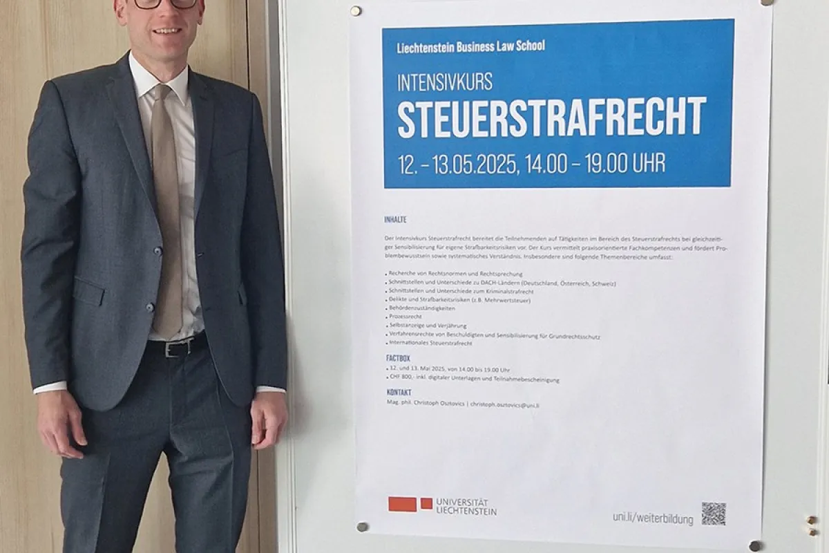 Ein Mann in Anzug steht neben einem Plakat, das den Intensivkurs „Steuerstrafrecht“ der Universität Liechtenstein ankündigt. Das Plakat enthält Informationen zu Datum, Uhrzeit und Inhalten des Kurses.