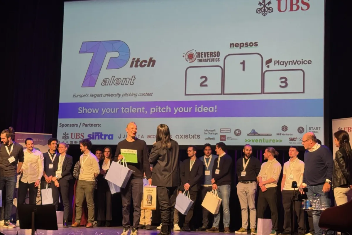 Eine Gruppe von Menschen steht auf einer Bühne beim Talent Pitch Switzerland im Volkshaus Zürich. Im Hintergrund ist eine Leinwand mit den Logos der Gewinner-Start-ups Reverso Therapeutics, Nepsos und PlaynVoice zu sehen. Die Veranstaltung wird von UBS gesponsert.