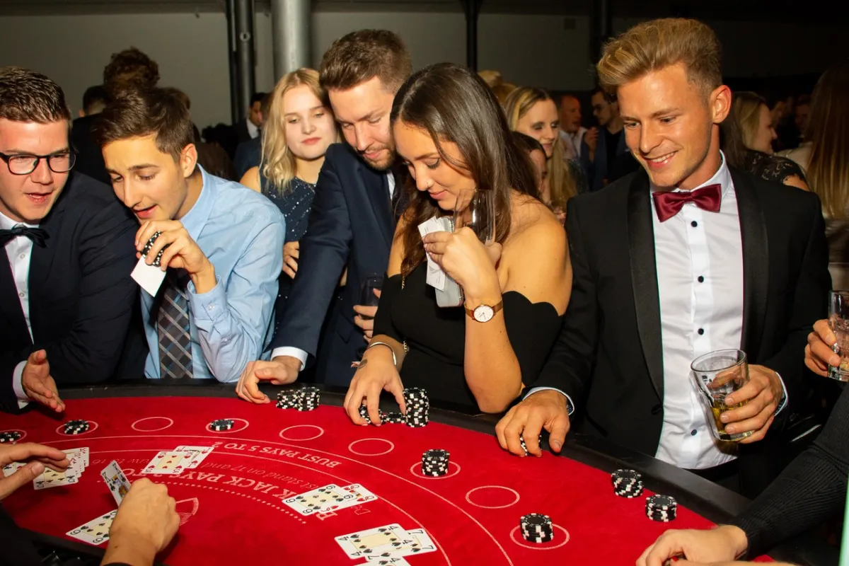 Studierende und Gäste der Universität Liechtenstein spielen in festlicher Abendkleidung an einem Blackjack-Tisch bei einer Campusveranstaltung.