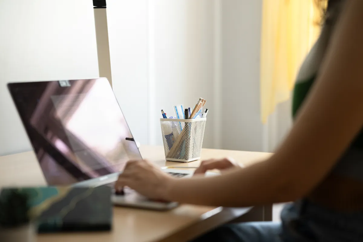 Studierende arbeitet am Laptop am Schreibtisch im Studierendenwohnheim der Universität Liechtenstein.