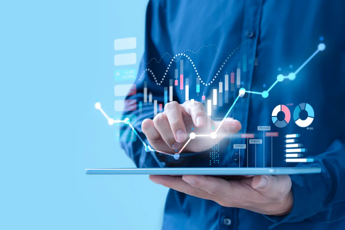 Person bedient Tablet mit eingeblendeten Finanzdiagrammen und Statistiken.