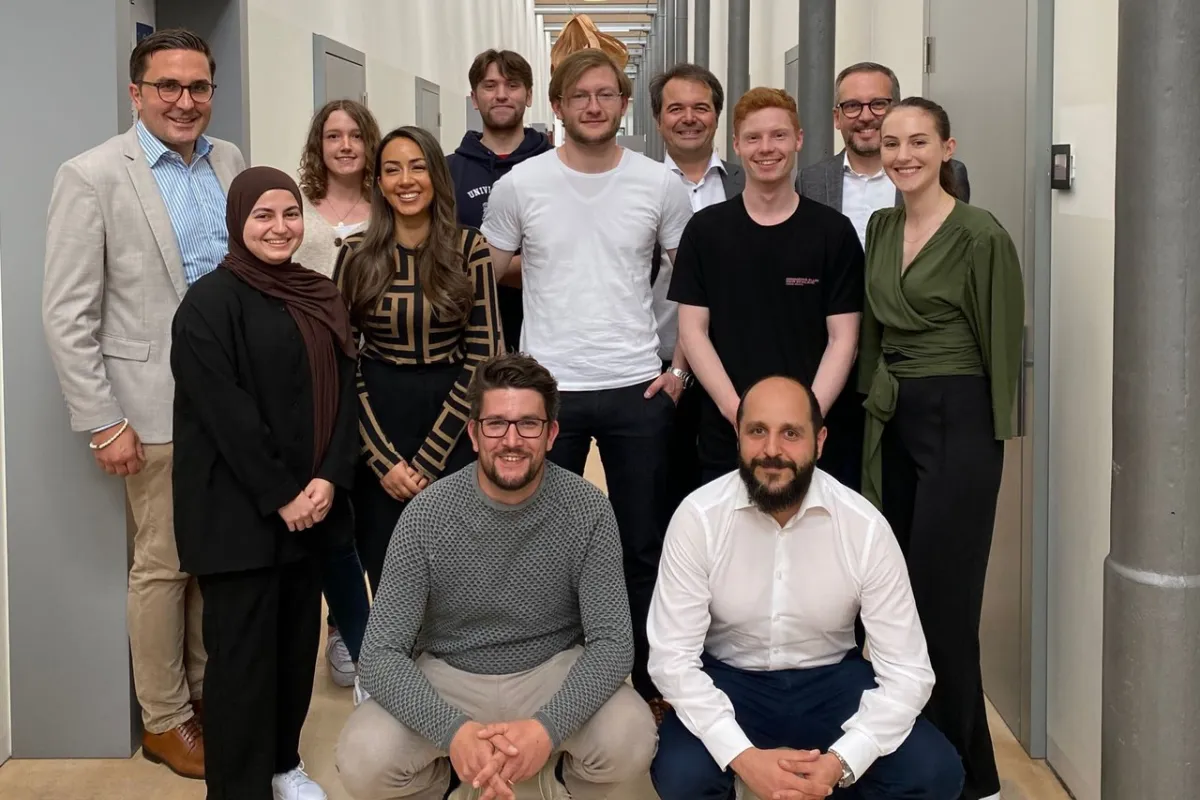Eine Gruppe von Studierenden und Dozenten der Universität Liechtenstein posiert in einem Flur. Sie nehmen an der Accenture Campus Innovation Challenge teil, die sich auf künstliche Intelligenz und innovative Technologien konzentriert.