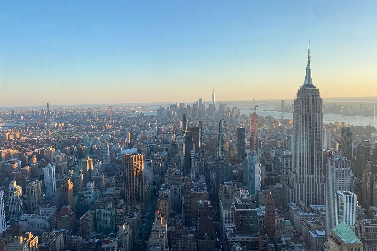 Luftaufnahme von New York City bei Sonnenuntergang, mit dem Empire State Building im Vordergrund und der Skyline im Hintergrund.