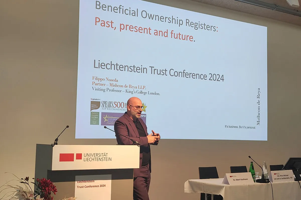 Ein Redner steht vor einem Podium mit dem Logo der Universität Liechtenstein und präsentiert bei der Liechtenstein Trust Conference 2024. Im Hintergrund ist eine Projektion mit dem Titel "Beneficial Ownership Registers: Past, present and future" zu sehen.