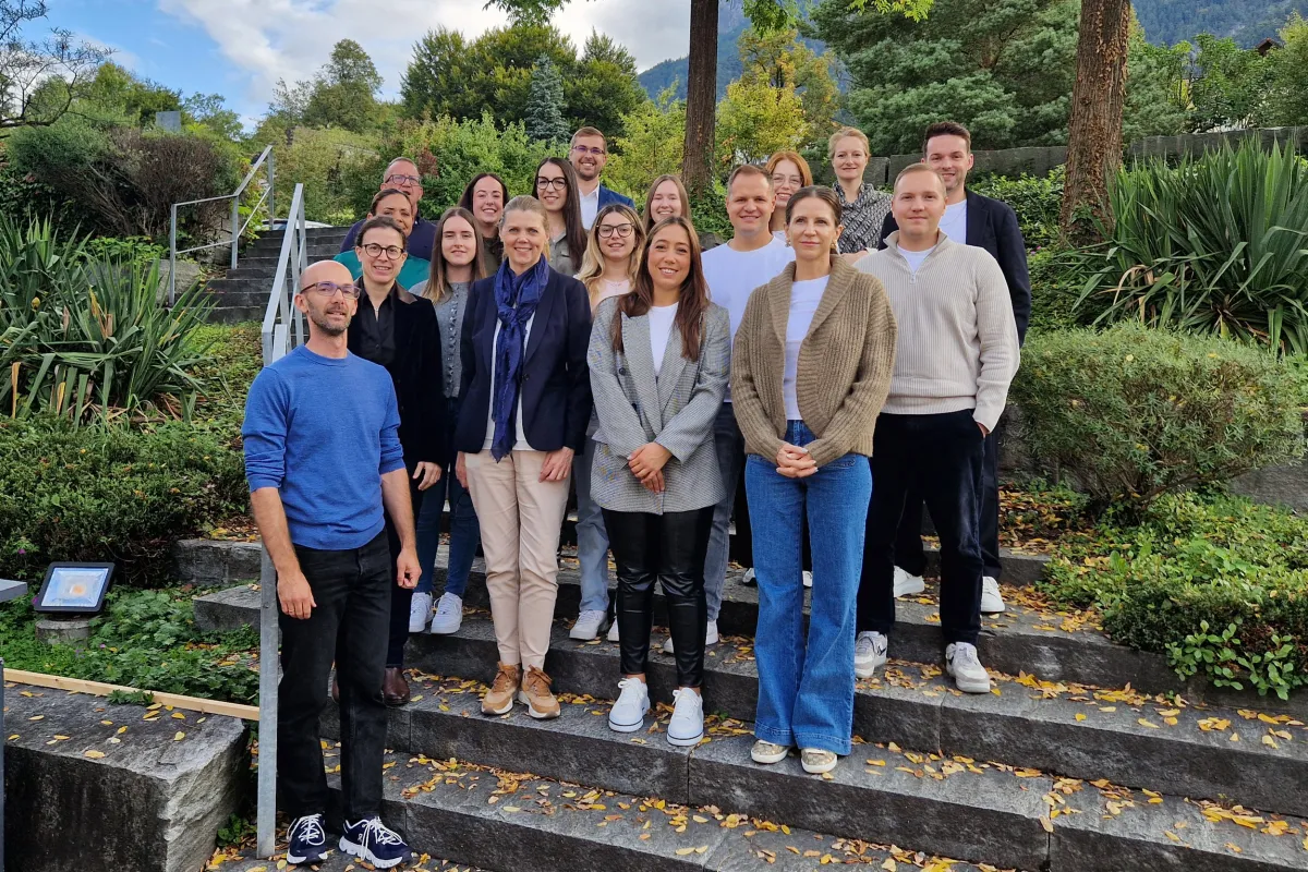 Gruppe von Erwachsenen steht auf Treppe in grüner Umgebung.