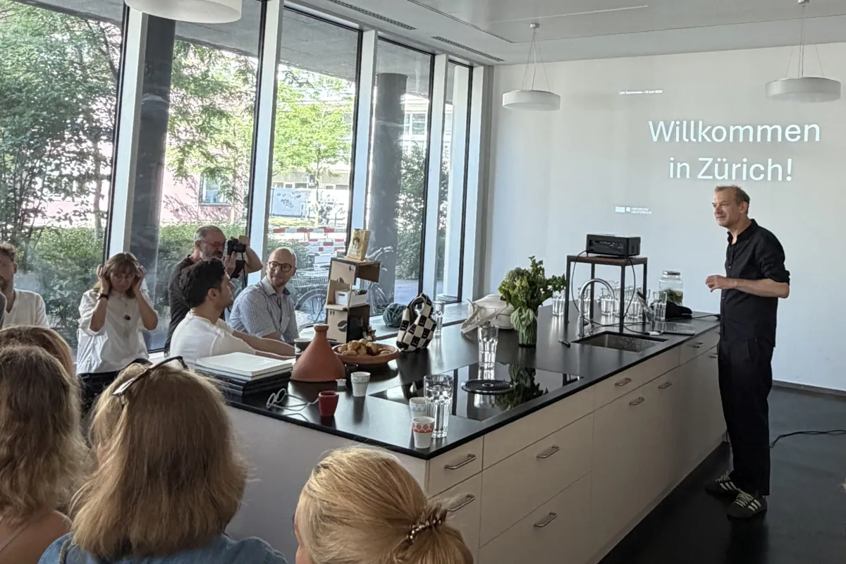 Vortragender an einem weissen Küchenblock mit Projektion an der Wand 