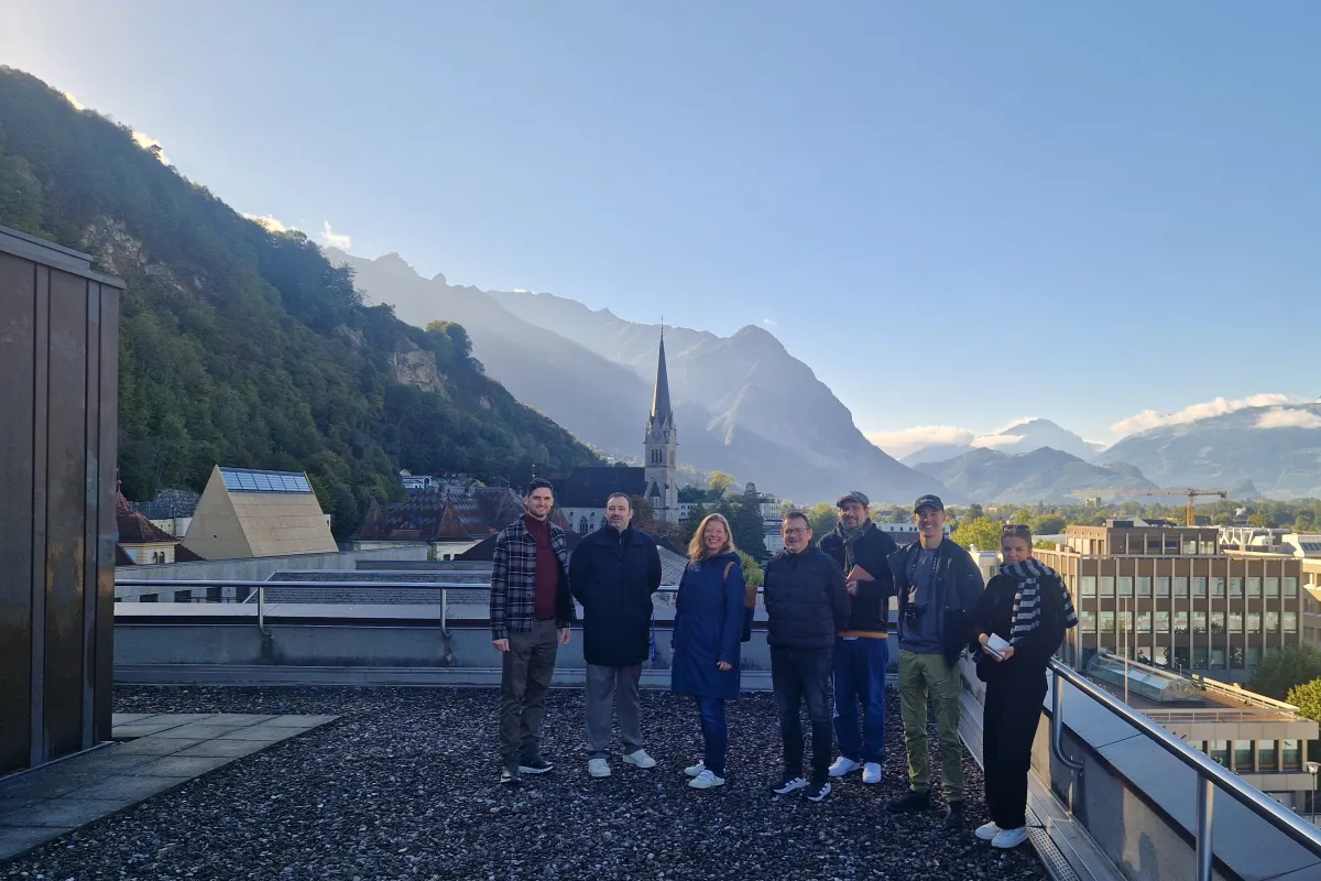 Eine Gruppe Menschen steht auf einem Dach und schaut in die Kamera