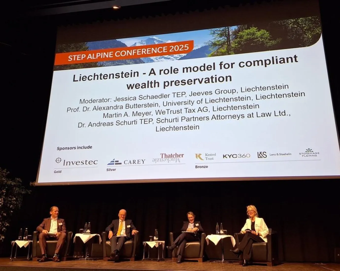 Podiumsdiskussion bei der STEP Alpine Conference 2025 mit vier Expertinnen und Experten auf einer Bühne vor einer großen Leinwand, die das Thema „Liechtenstein – A role model for compliant wealth preservation“ zeigt.
