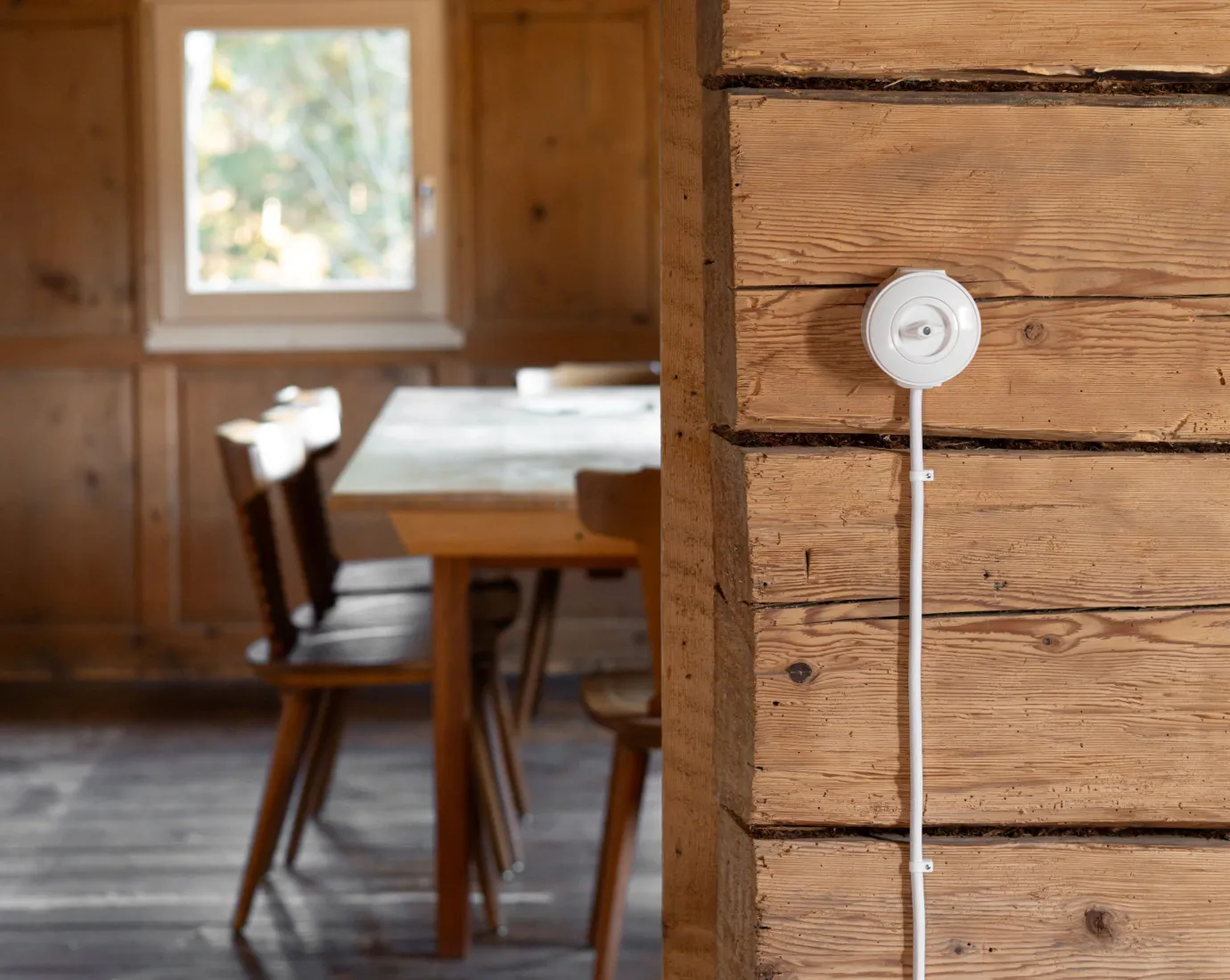 Ein weisser Lichtschalter an einer Altholzwand