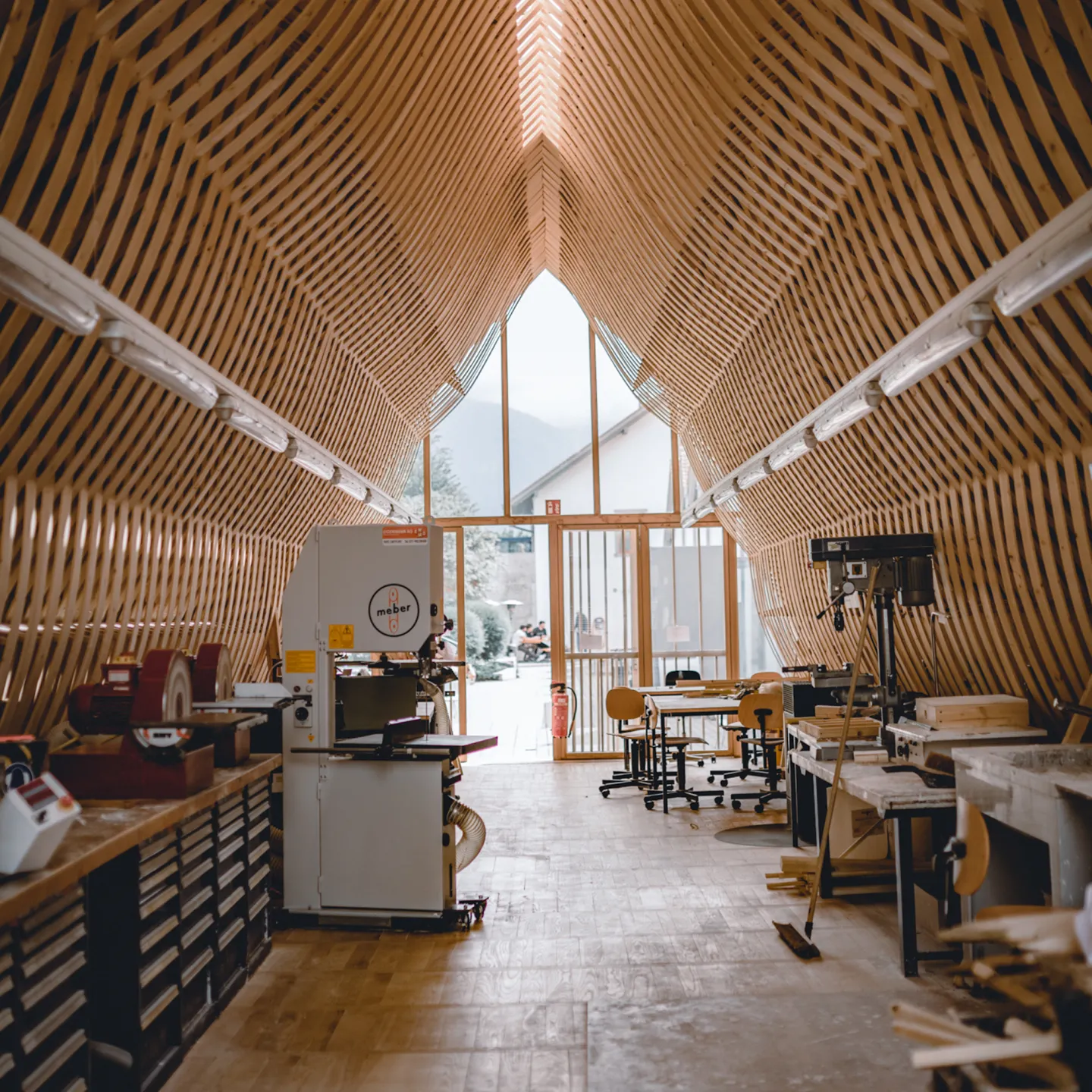 Gesamtsicht der hellen Holzwerkstatt mit Maschinen, Werkbänken und Fenstern
