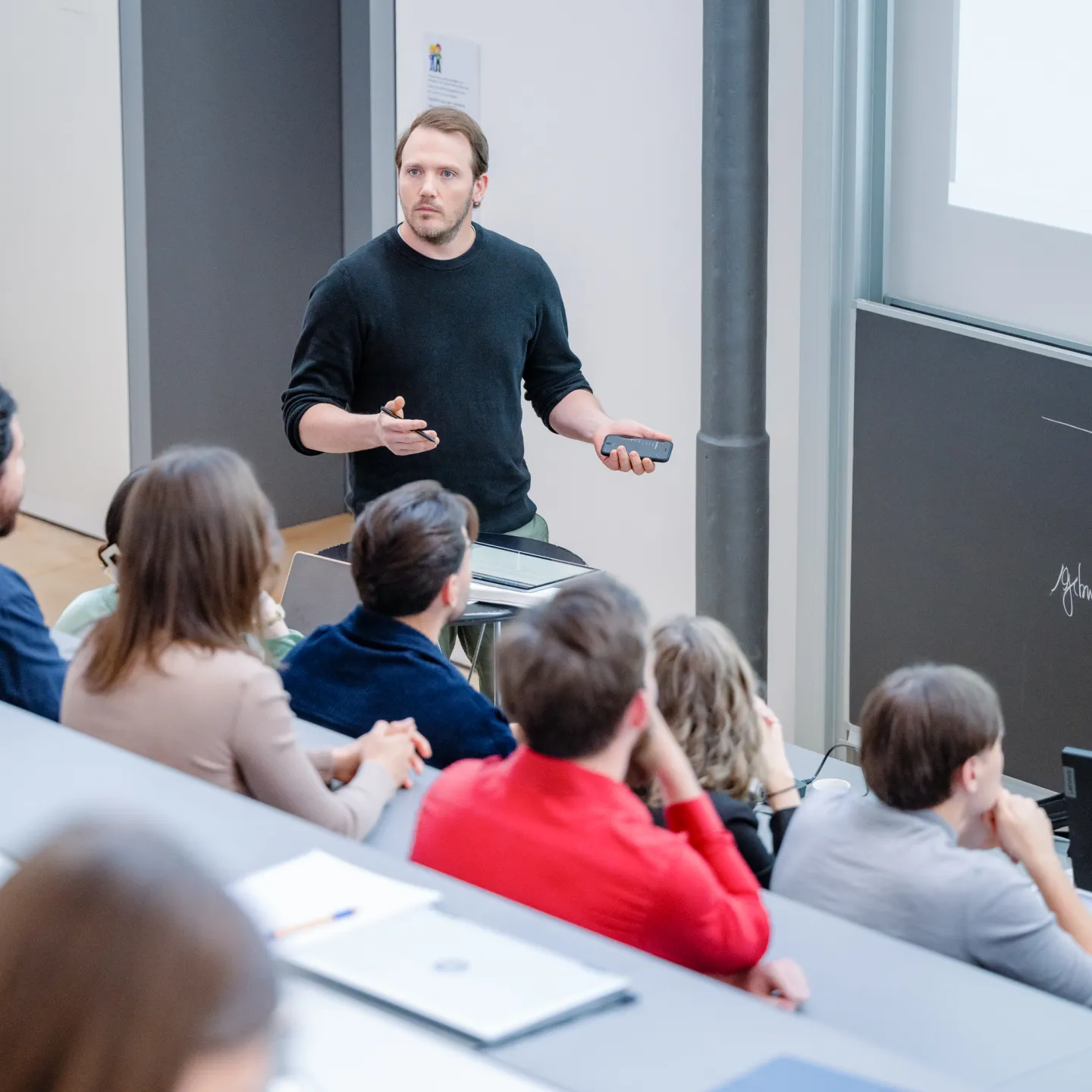 Ein Dozent hält eine Präsentation im Hörsaal der Universität Liechtenstein vor einer Gruppe Studierender.