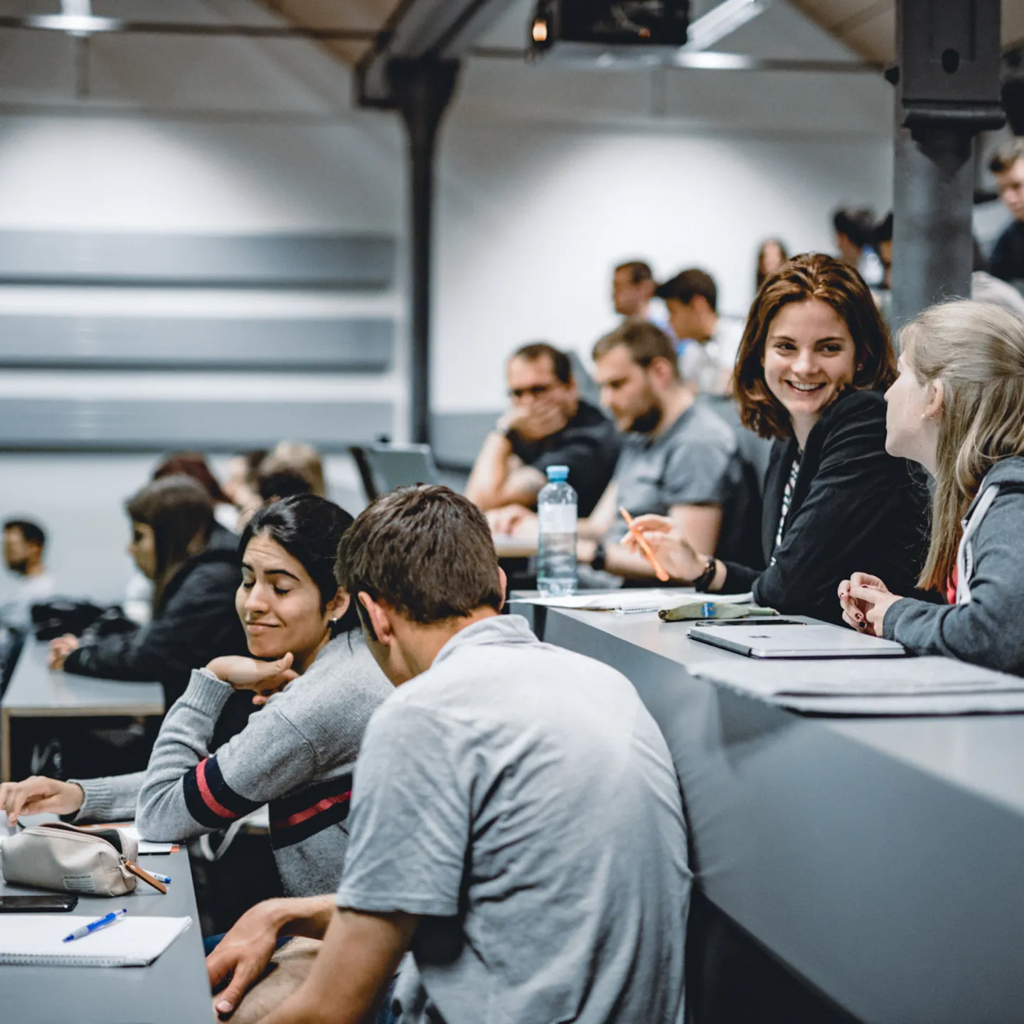 Studierende der Universität Liechtenstein sitzen im Hörsaal und unterhalten sich vor Beginn einer Vorlesung.