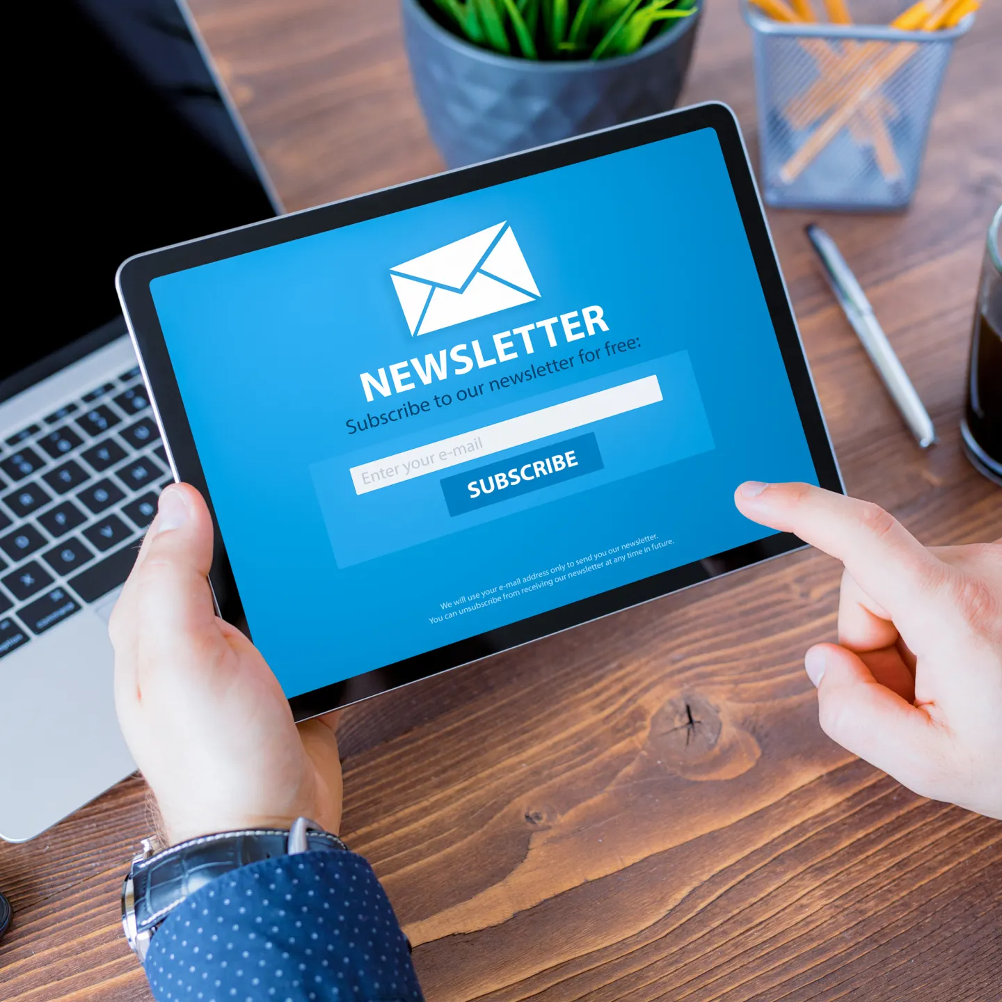 Tablet mit geöffneter Newsletter-Anmeldung auf einem Schreibtisch mit Bürobedarf