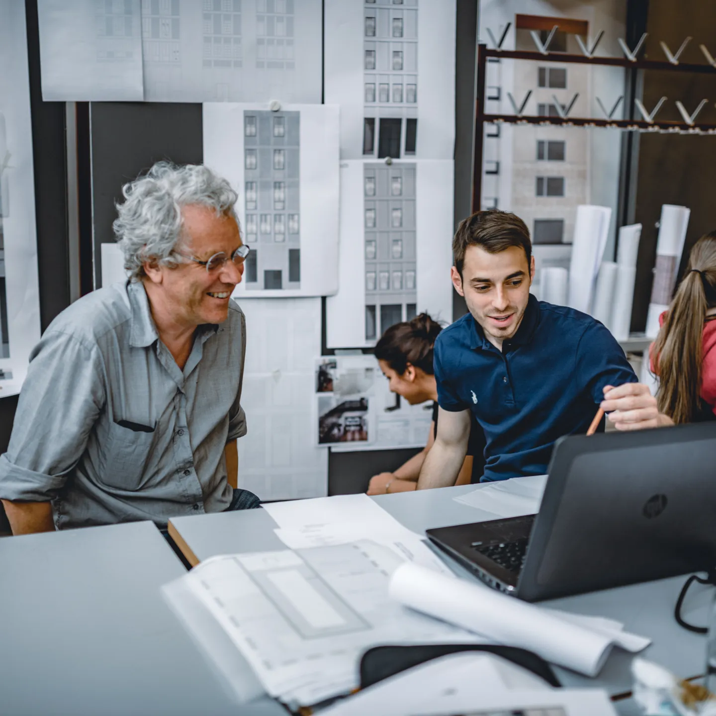 PhD Studierende und Dozierender im Bereich Architektur der Universität Liechtenstein im intensiven Austausch über Entwurfspläne im Architekturstudio.
