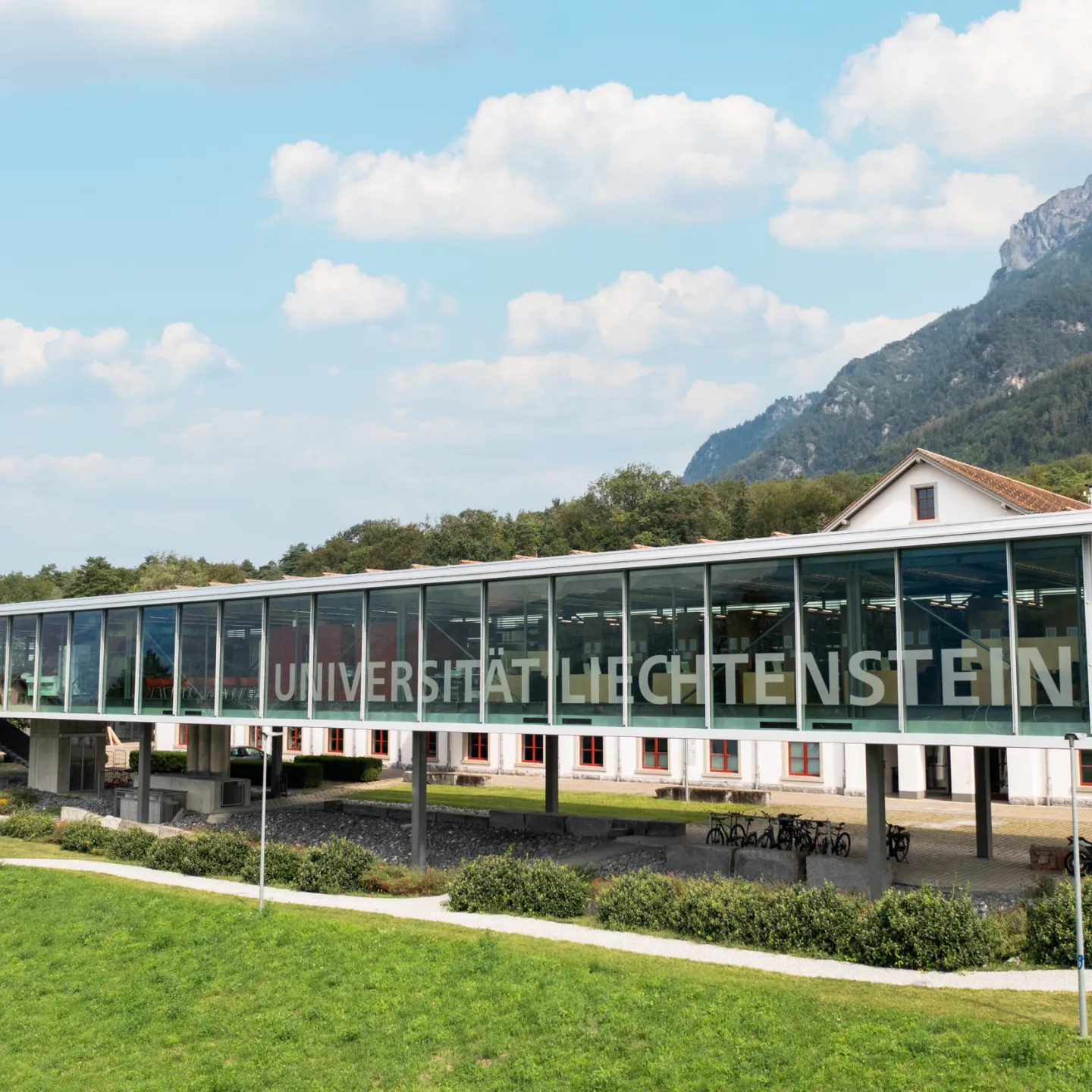 Moderne Glasfassade der Universität Liechtenstein mit Blick auf das Alpenpanorama.