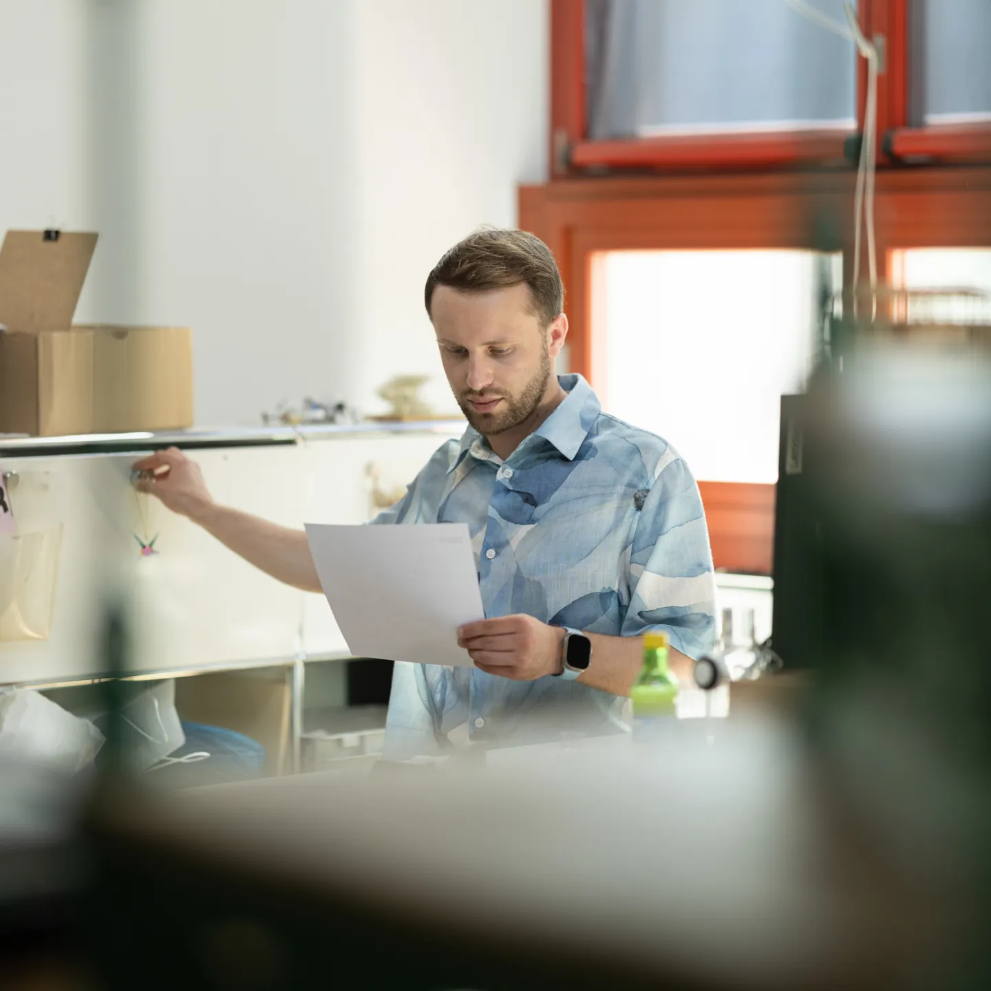 Student arbeitet im Büro an der Universität Liechtenstein und liest ein Dokument.