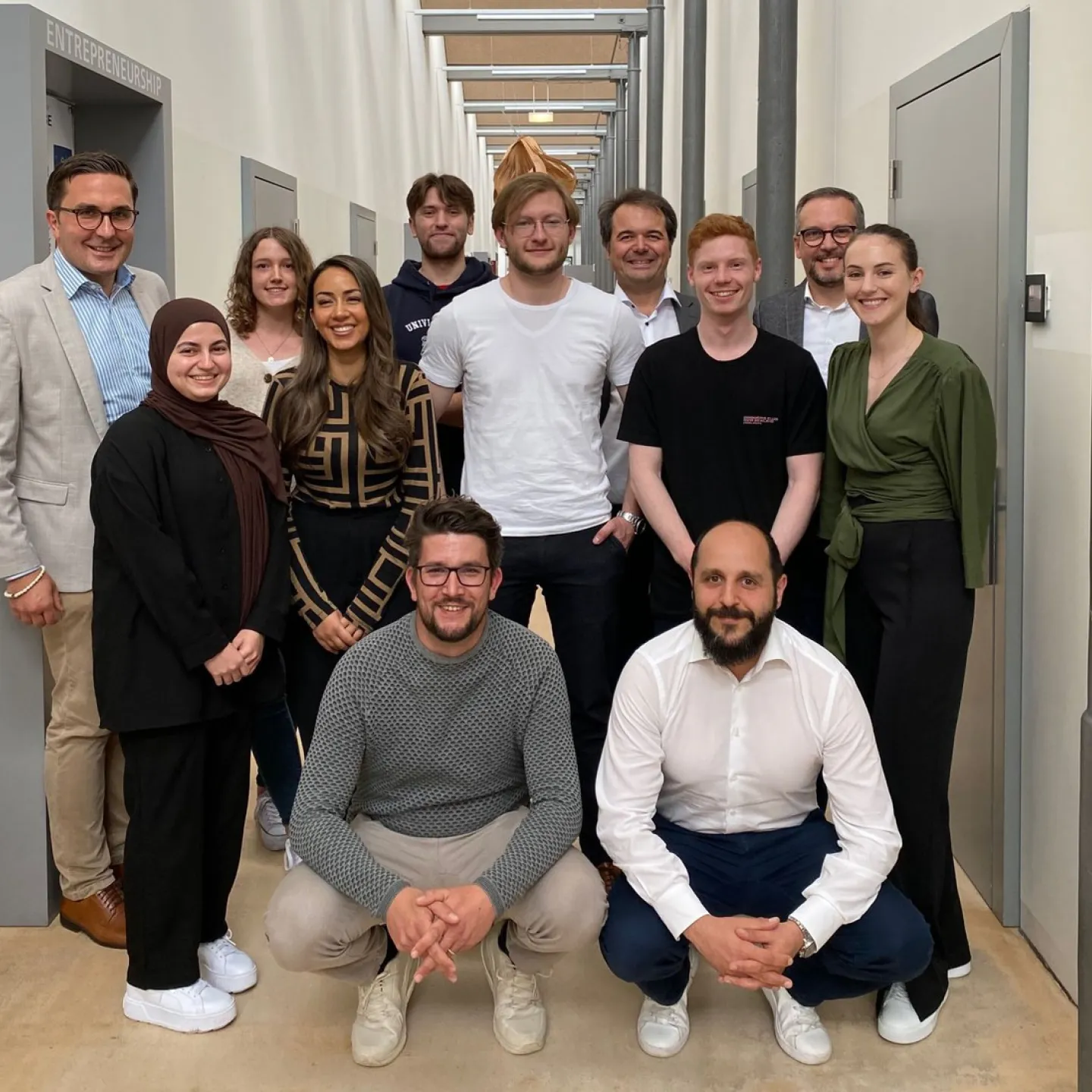 Eine Gruppe von Studierenden und Dozenten der Universität Liechtenstein posiert in einem Flur. Sie nehmen an der Accenture Campus Innovation Challenge teil, die sich auf künstliche Intelligenz und innovative Technologien konzentriert.
