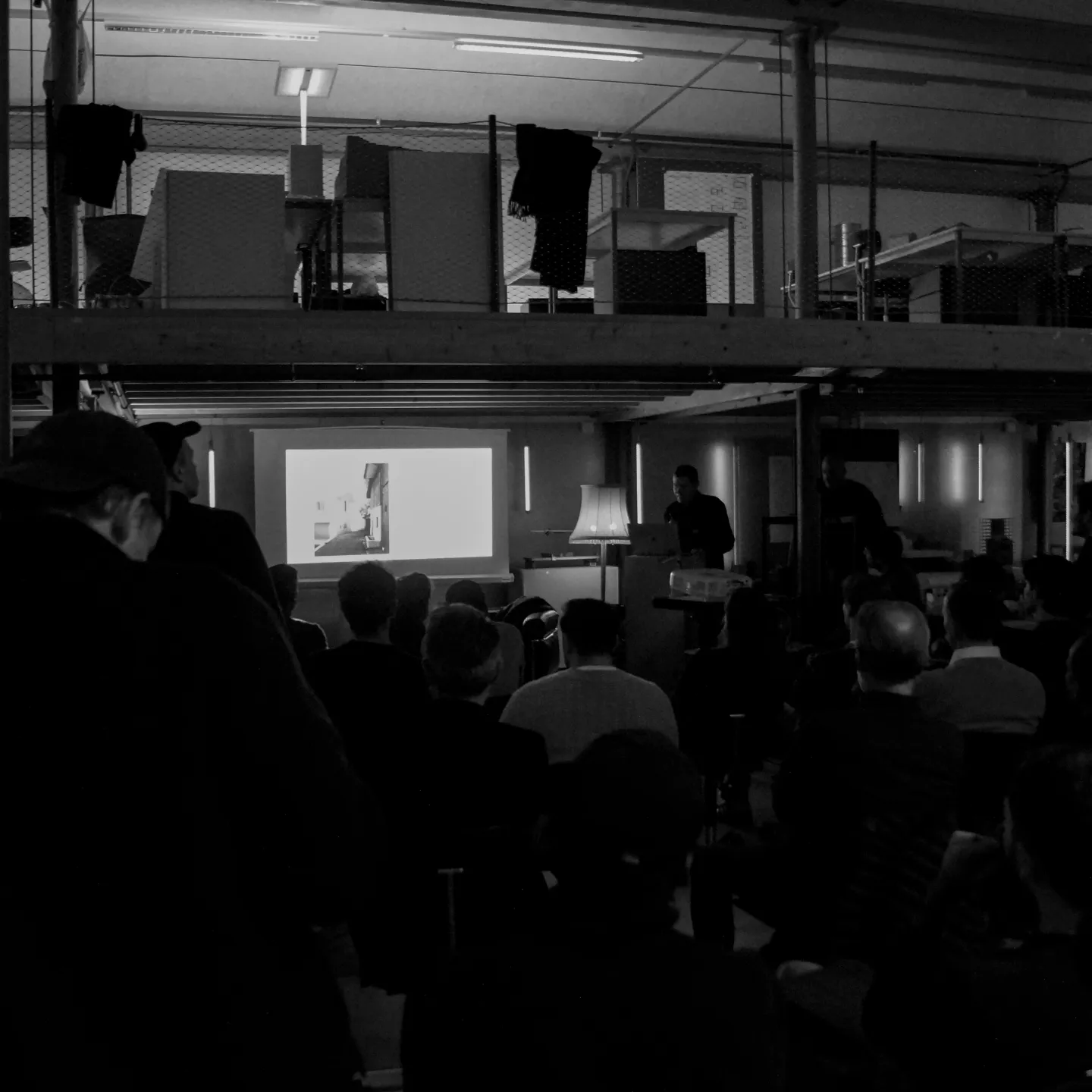 Schwarz/weiss Aufnahme mit Publikum und Vortragendem