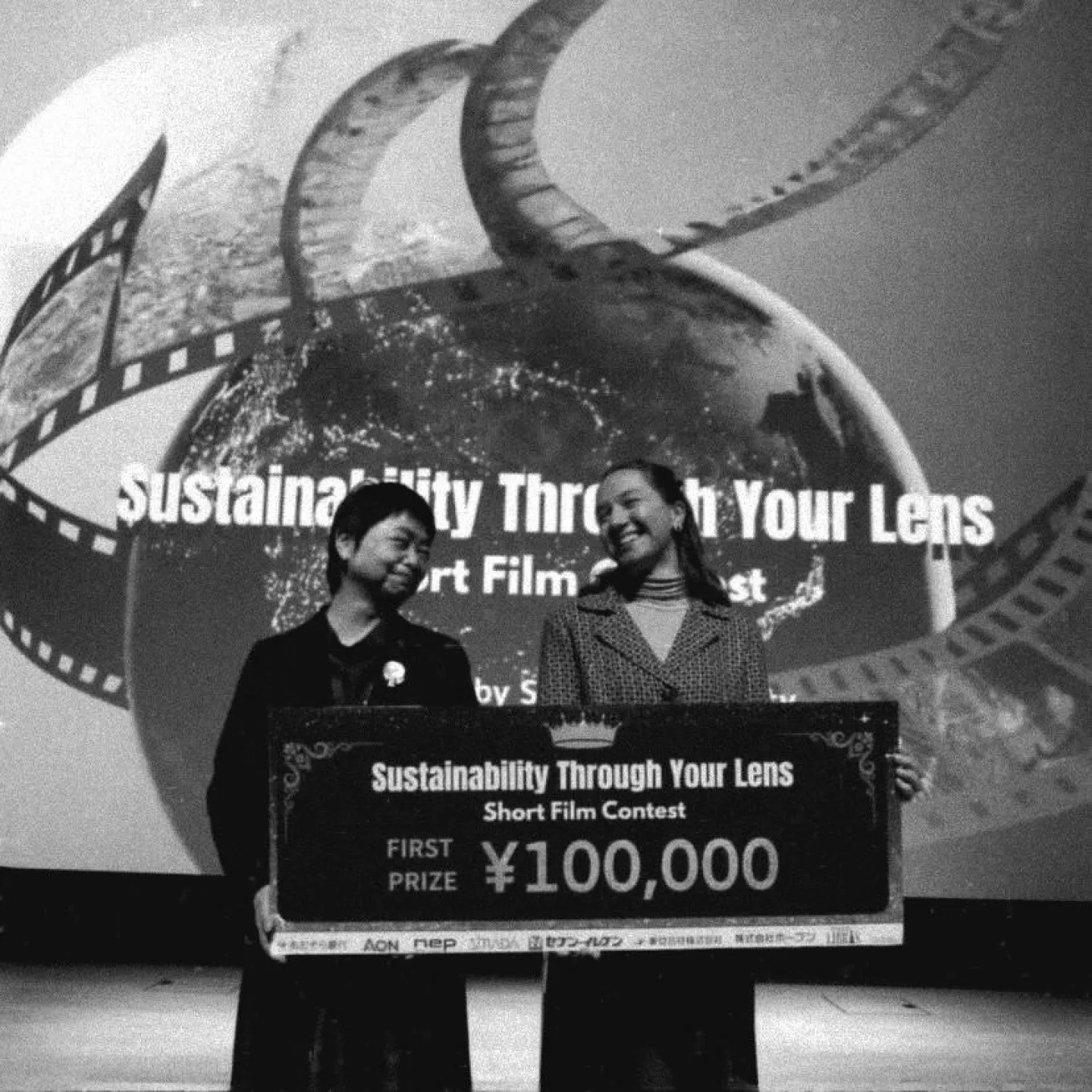 Schwarz-Weiss Aufnahme von zwei Frauen mit einem grossen Scheck in der Hand