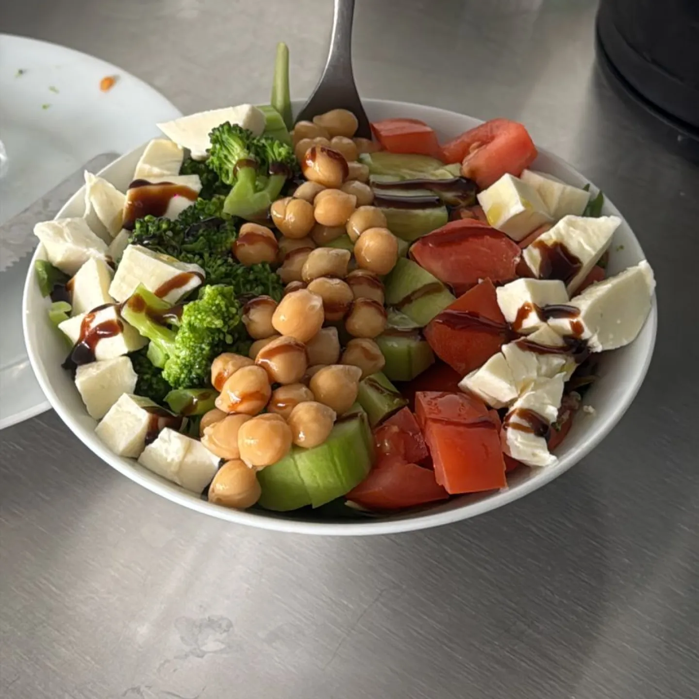Bowl of salad with chickpeas, vegetables, and cheese.